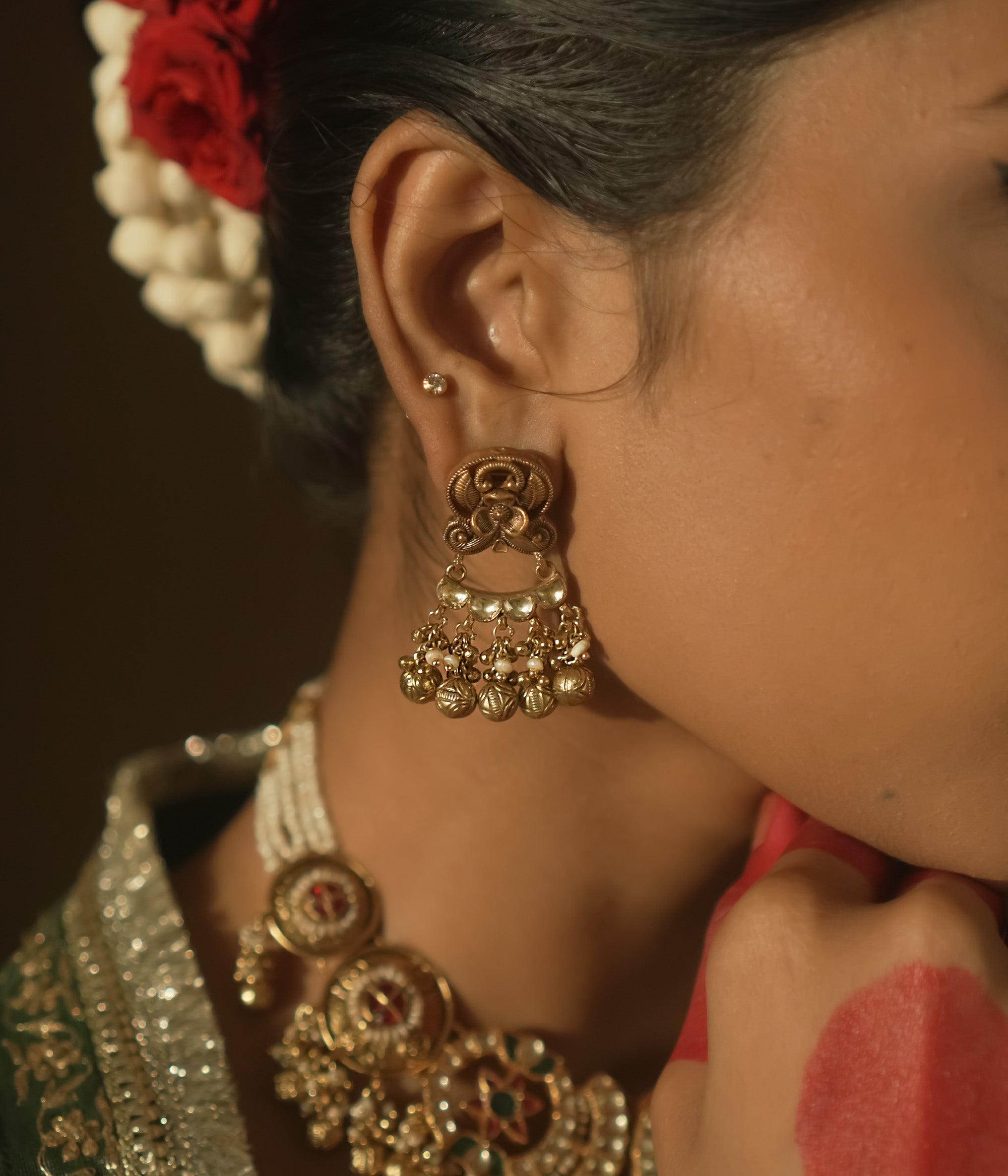 Gold chaandbali earrings with intricate swirls, red Kundan stones, and tiny bells.