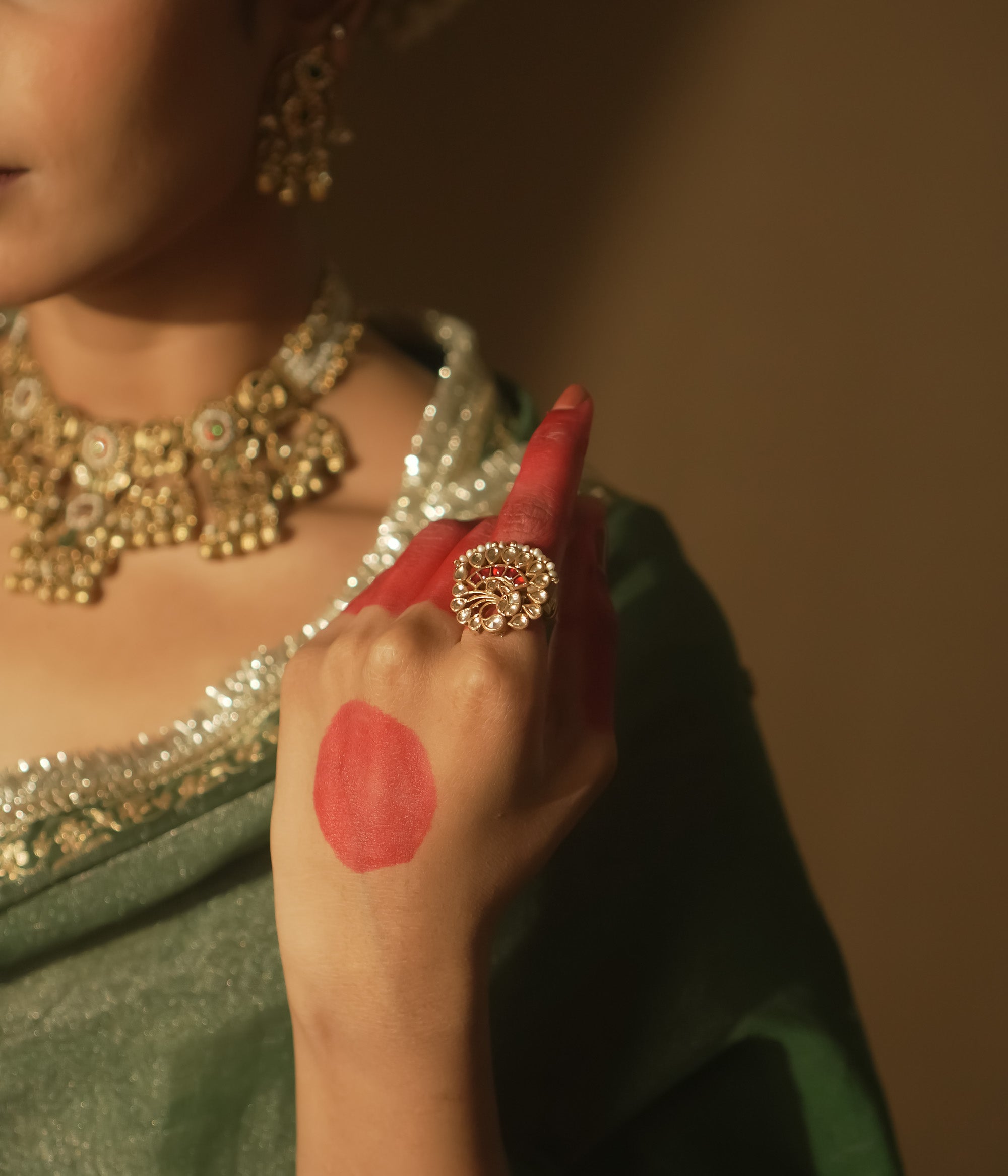 Gold-plated silver filigree ring with a central red Kundan stone and pearls.