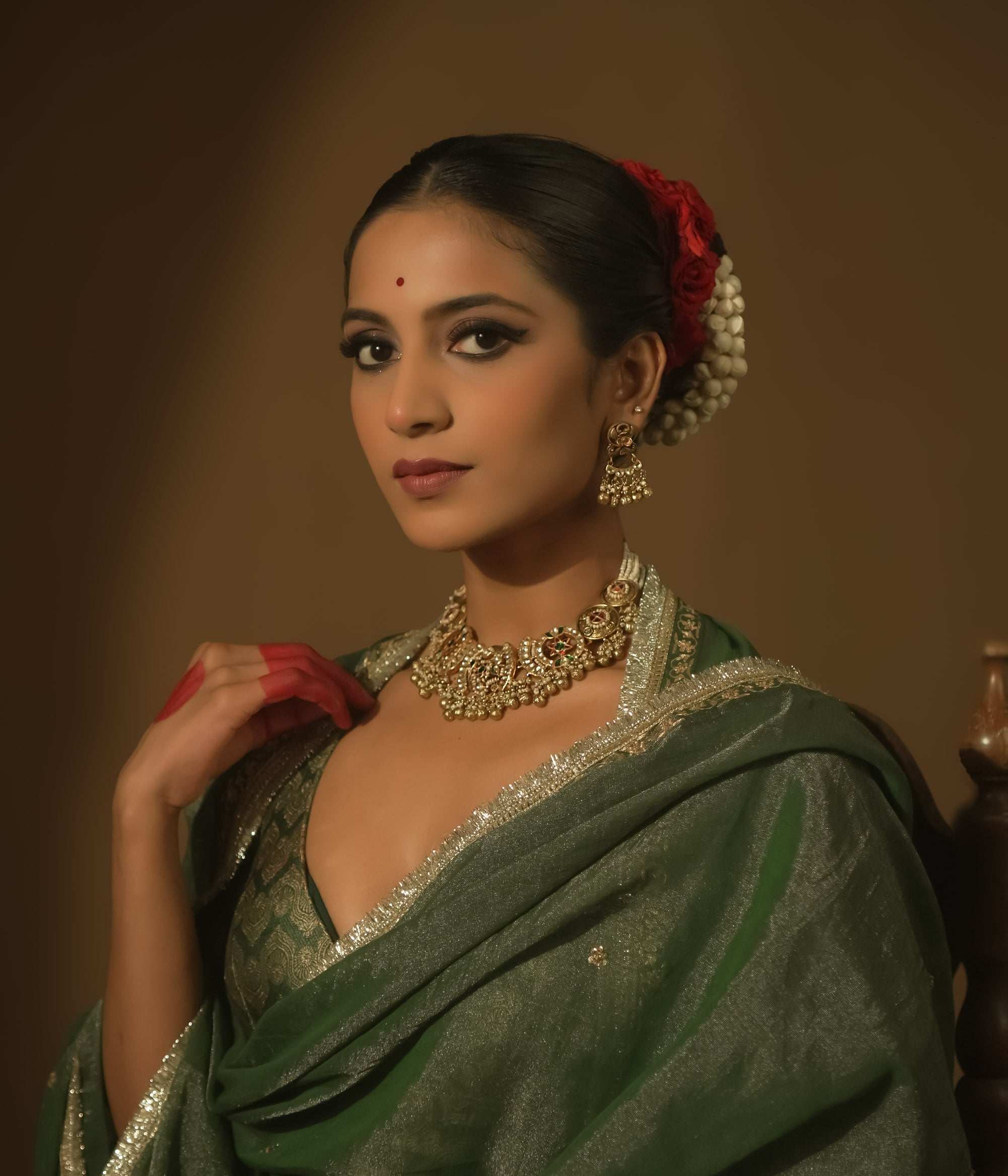 Gold-plated silver necklace with crescent motifs, red, green, and clear Kundan stones, and bells.