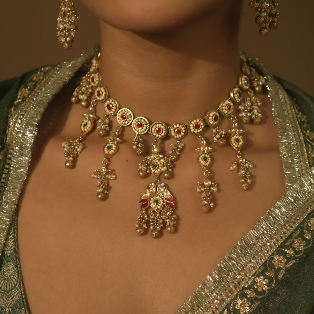 Gold-plated silver necklace with intricate loops, green Kundan, and pearls.
