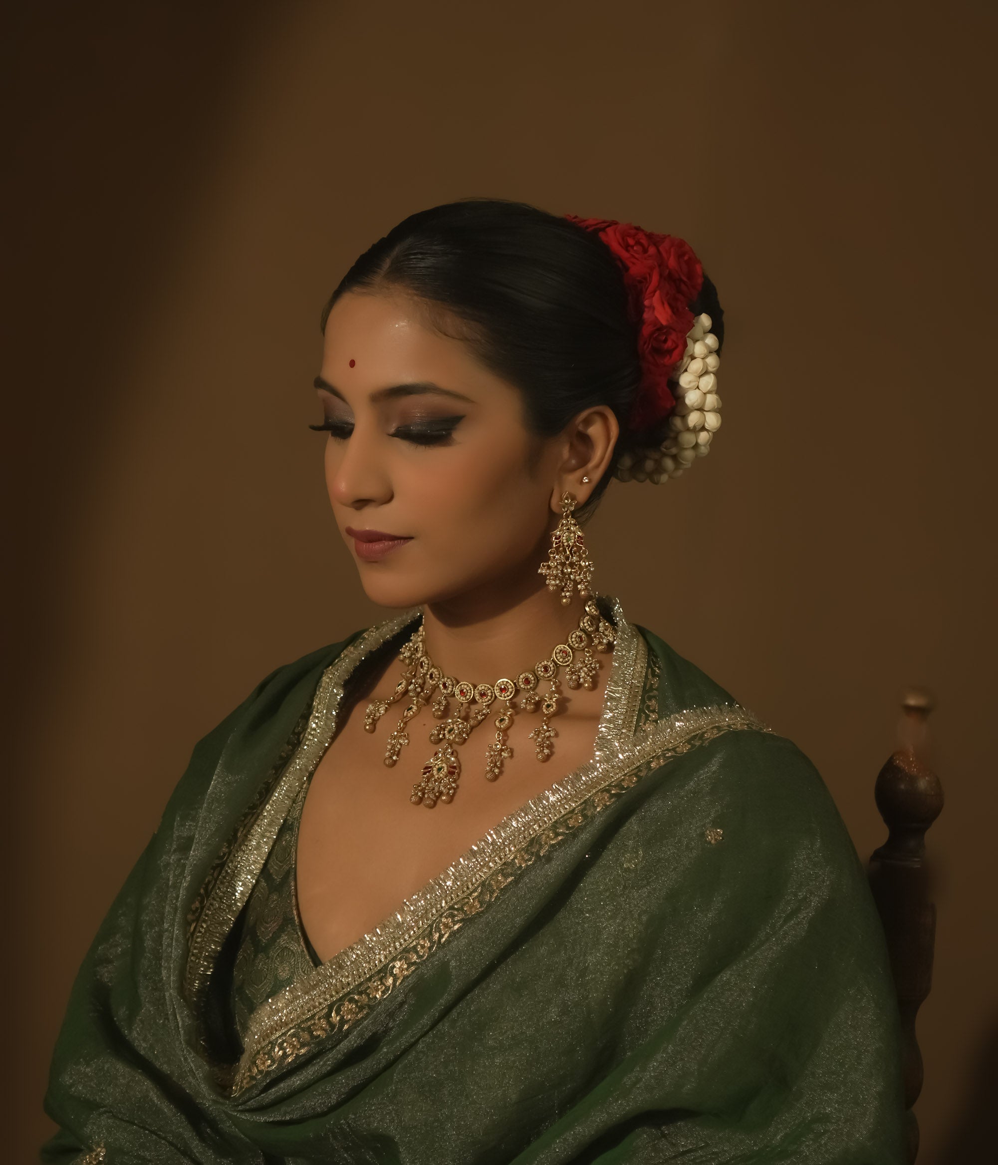 Gold-plated silver necklace with intricate loops, green Kundan, and pearls.