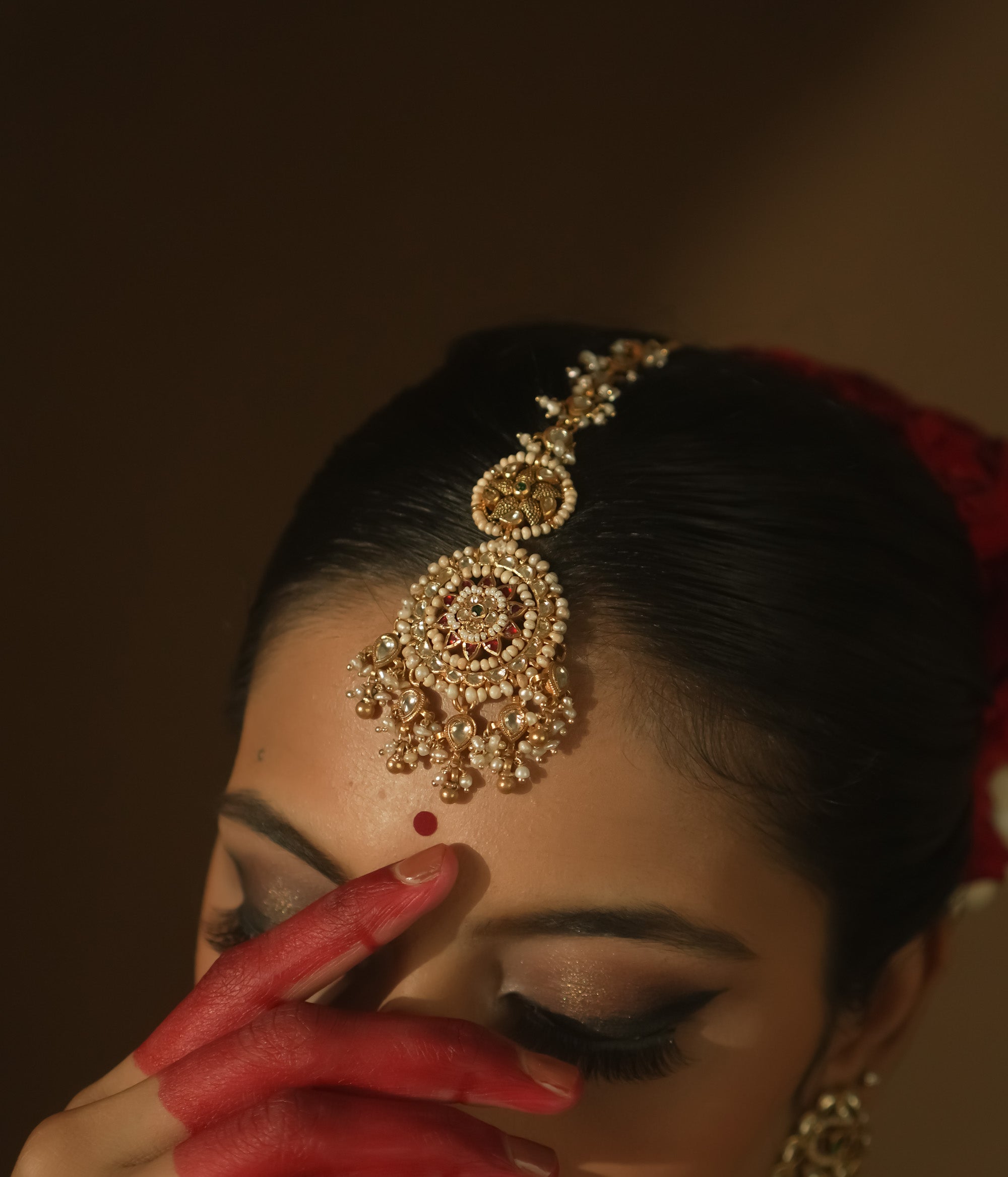Gold maangtika with filigree, Kundan stones, and a large medallion with pearl drops.