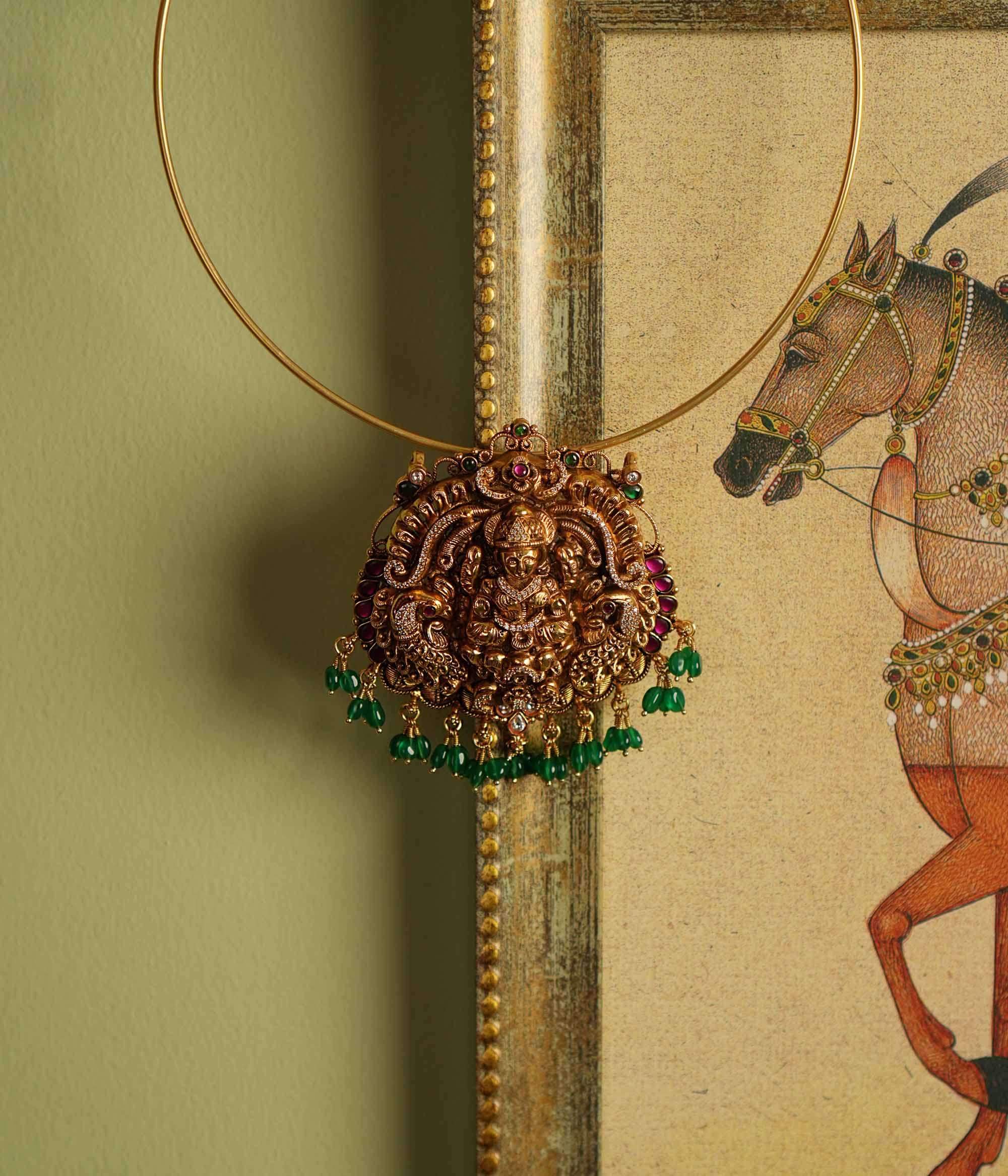 Traditional gold-plated silver temple jewelry pendant featuring Goddess Lakshmi at the center, adorned with radiant red and green Kundan stones and elegant strawberry quartz drops. Designed with both single and double hooks for versatile styling, this pendant exudes divine grace and timeless craftsmanship.