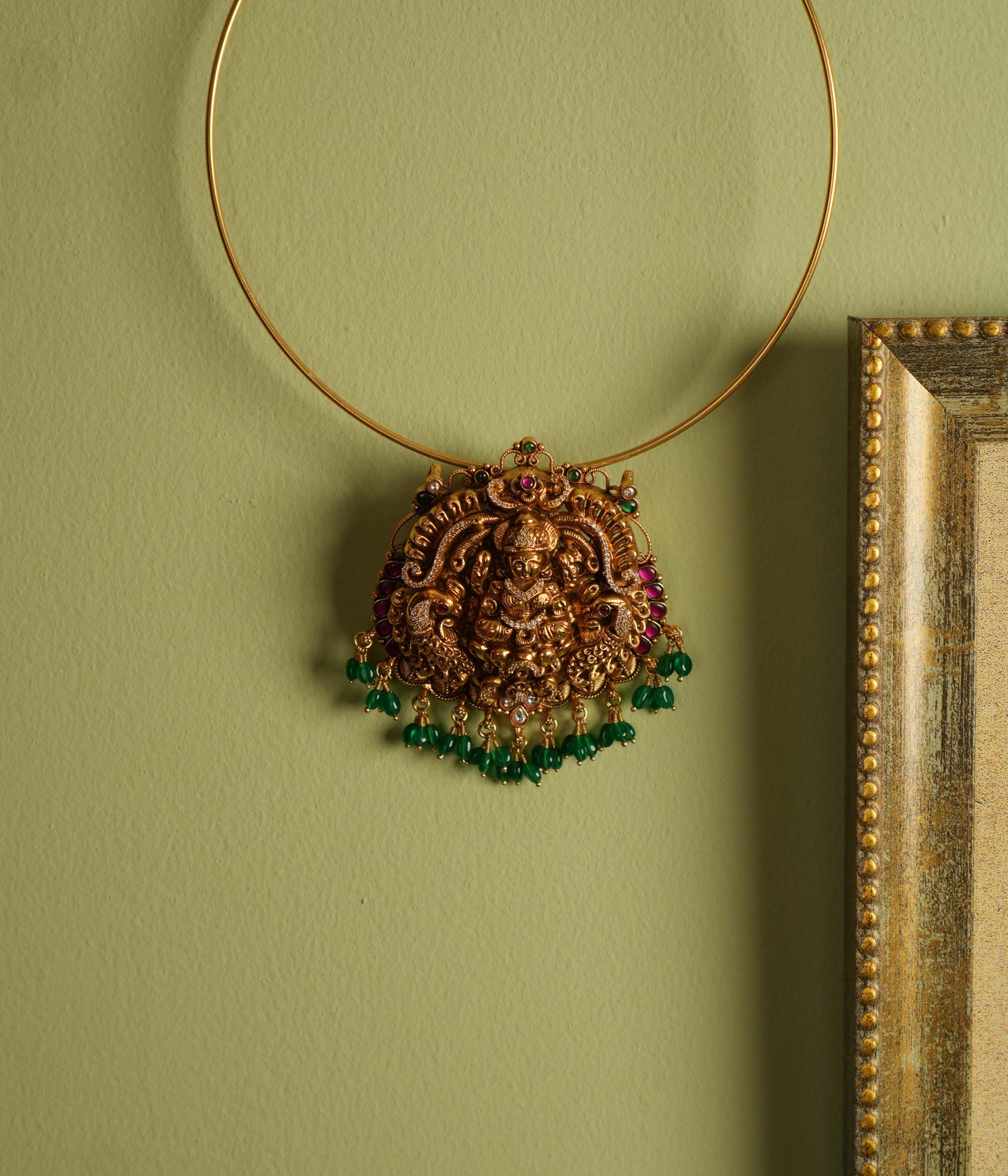 Traditional gold-plated silver temple jewelry pendant featuring Goddess Lakshmi at the center, adorned with radiant red and green Kundan stones and elegant strawberry quartz drops. Designed with both single and double hooks for versatile styling, this pendant exudes divine grace and timeless craftsmanship.