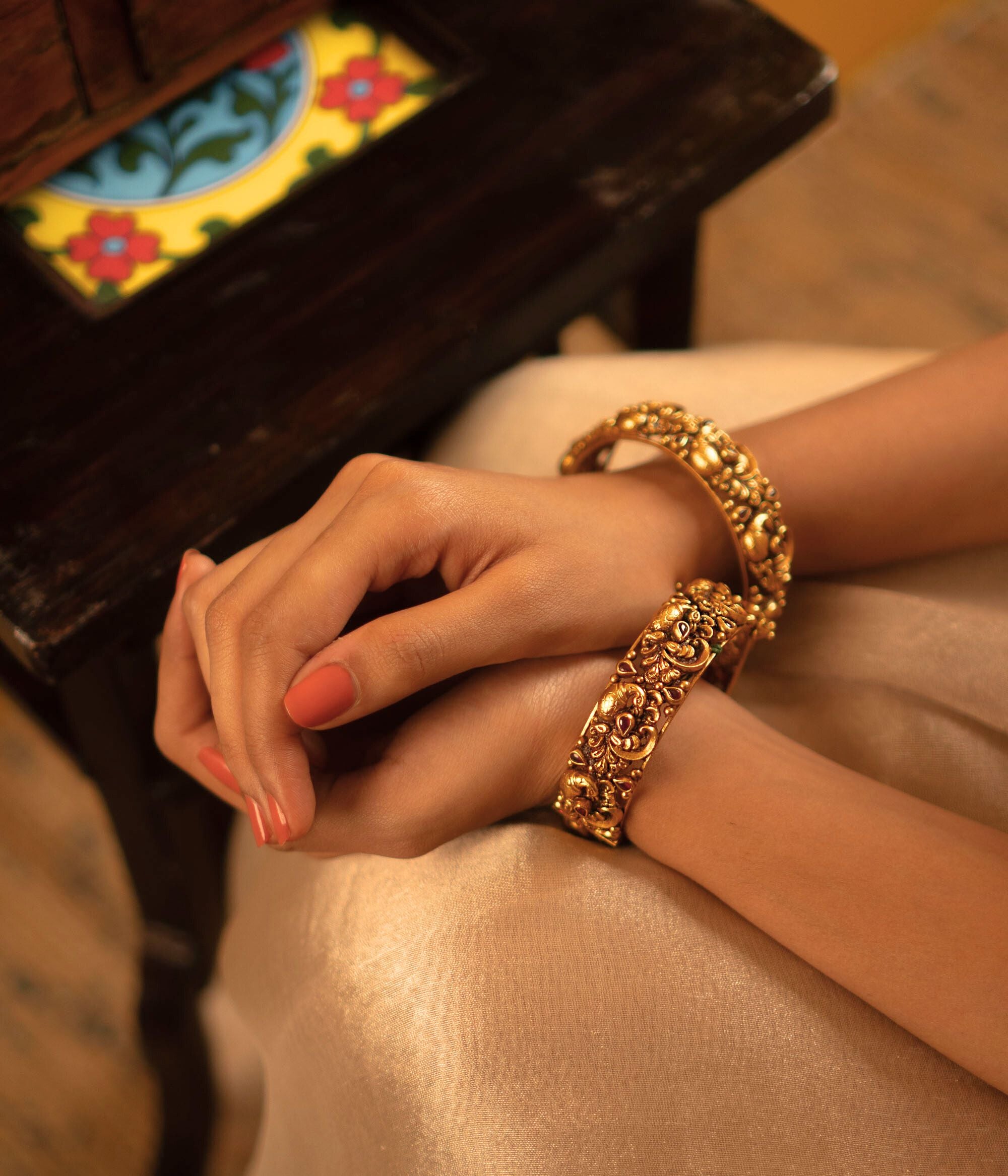 The Jagvi Kada, meticulously handcrafted in antique gold-plated silver, showcases exquisite temple-inspired details with pink kundans set in a classic kaairi pattern, reflecting timeless heritage and craftsmanship.