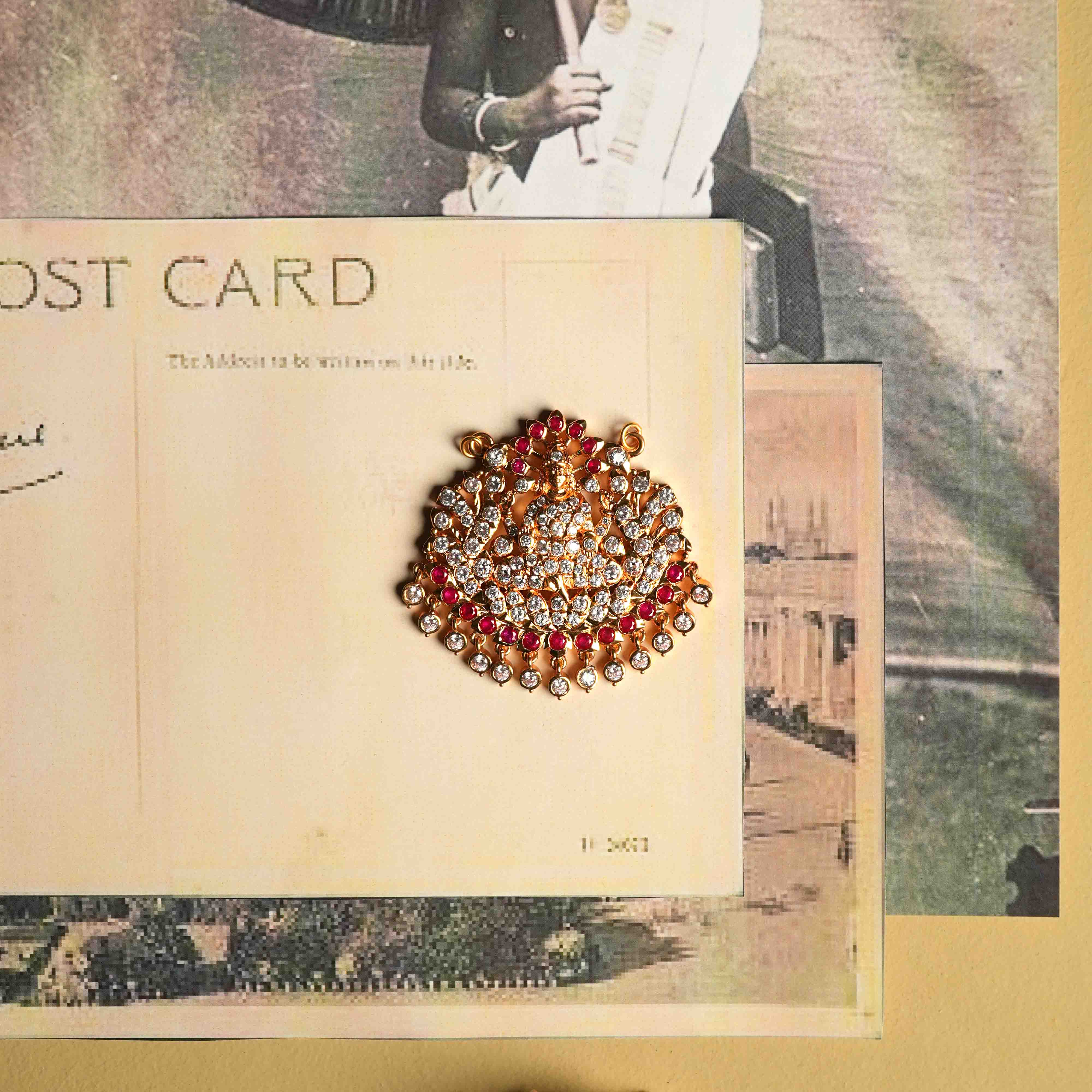 This moissanite pendant, crafted from 92.5 sterling silver with a South screw fastening, showcases an intricate deity motif accented with red cut stones and Swarovski crystals, inspired by vintage Chettinad stone settings.