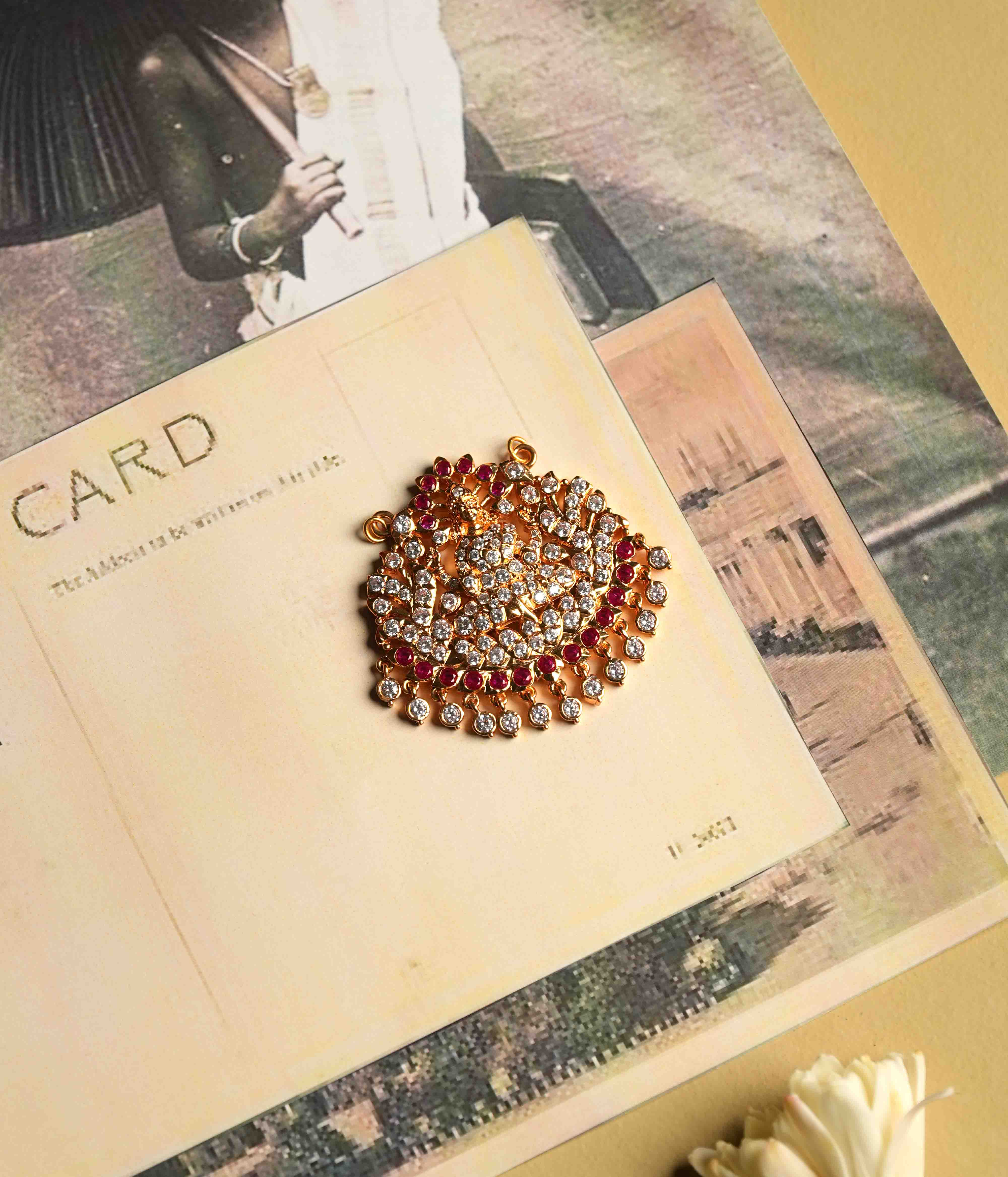 This moissanite pendant, crafted from 92.5 sterling silver with a South screw fastening, showcases an intricate deity motif accented with red cut stones and Swarovski crystals, inspired by vintage Chettinad stone settings.