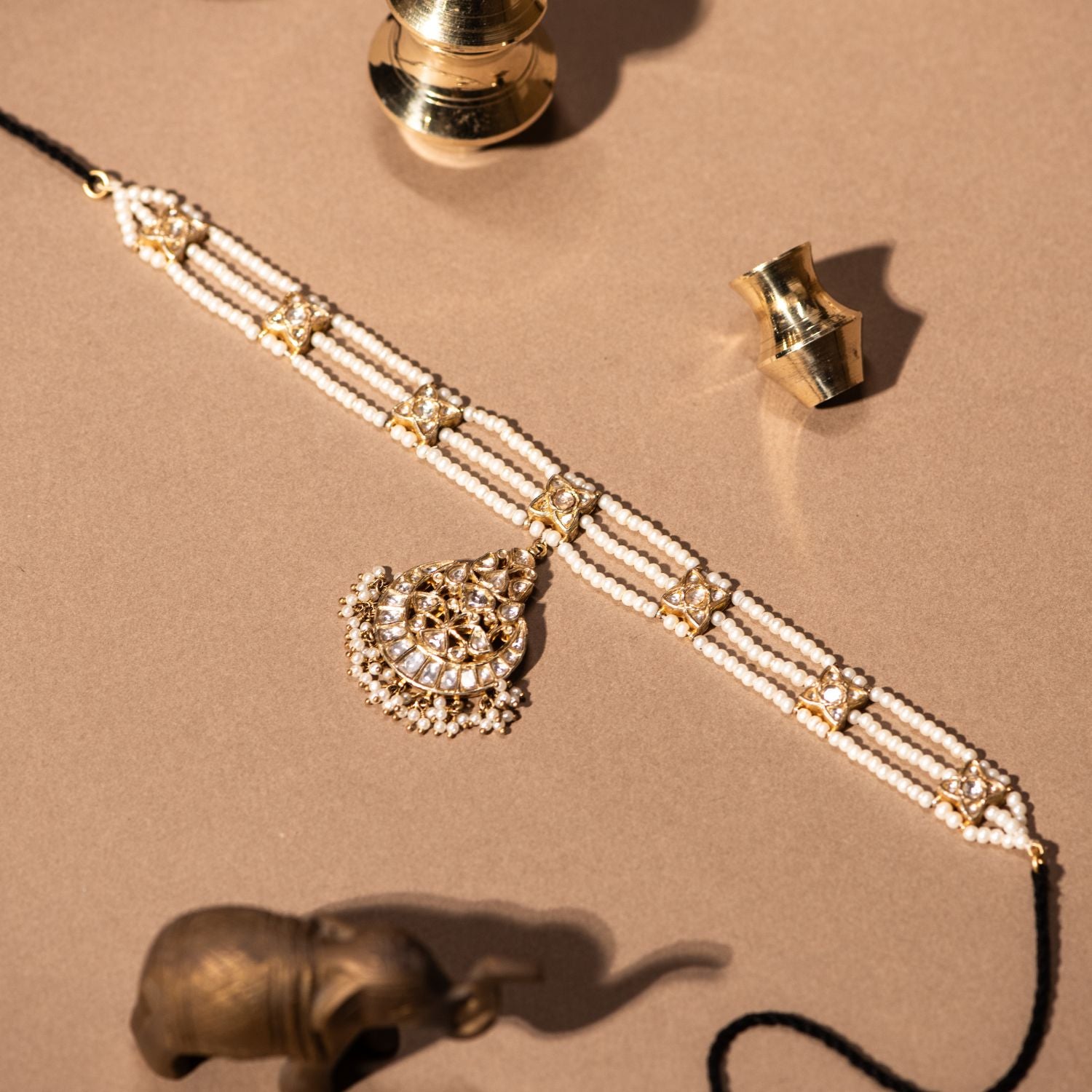 Gold-plated silver tikka featuring a delicate moon-shaped pendant, adorned with shimmering white sapphires and elegant pearls, exuding a timeless and graceful traditional charm.