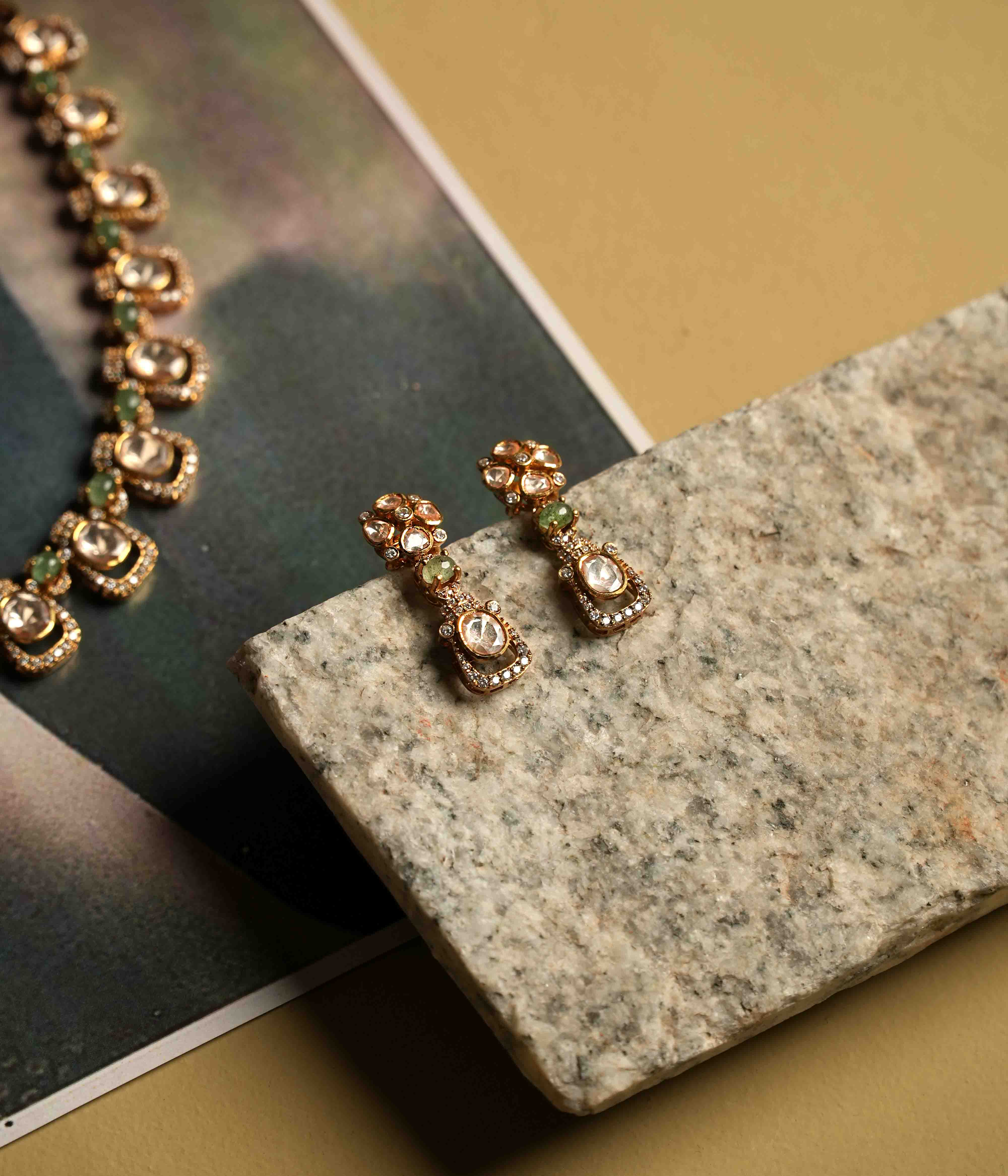 A delicate polki and moissanite necklace with matching drop earrings, crafted from handmade 92.5 sterling silver with 22ct gold plating, and accented with green tourmaline cut stones and CZ stones, embodying urban elegance and contemporary luxury.
