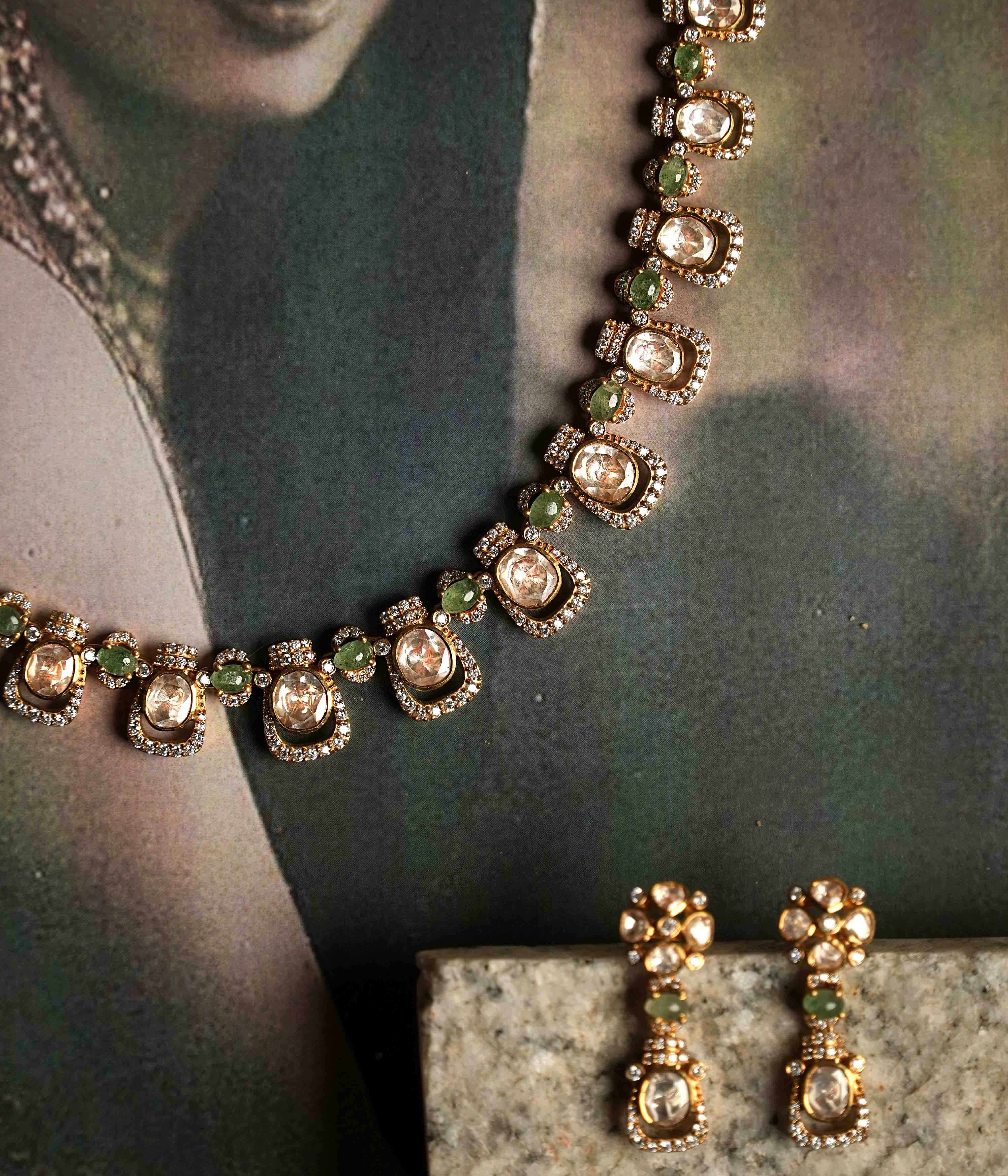 A delicate polki and moissanite necklace with matching drop earrings, crafted from handmade 92.5 sterling silver with 22ct gold plating, and accented with green tourmaline cut stones and CZ stones, embodying urban elegance and contemporary luxury.