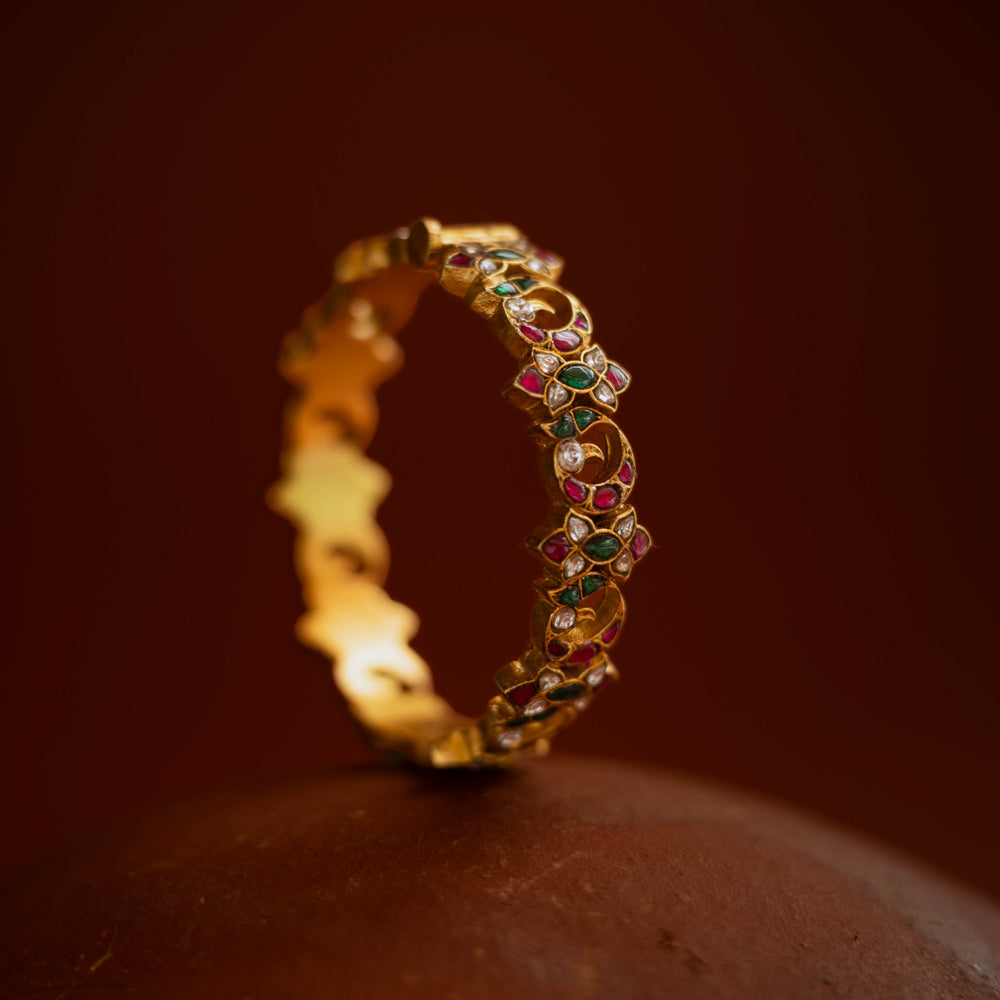 Kundan bangle with alternating moon and floral motifs, set in red, green, white stones.
