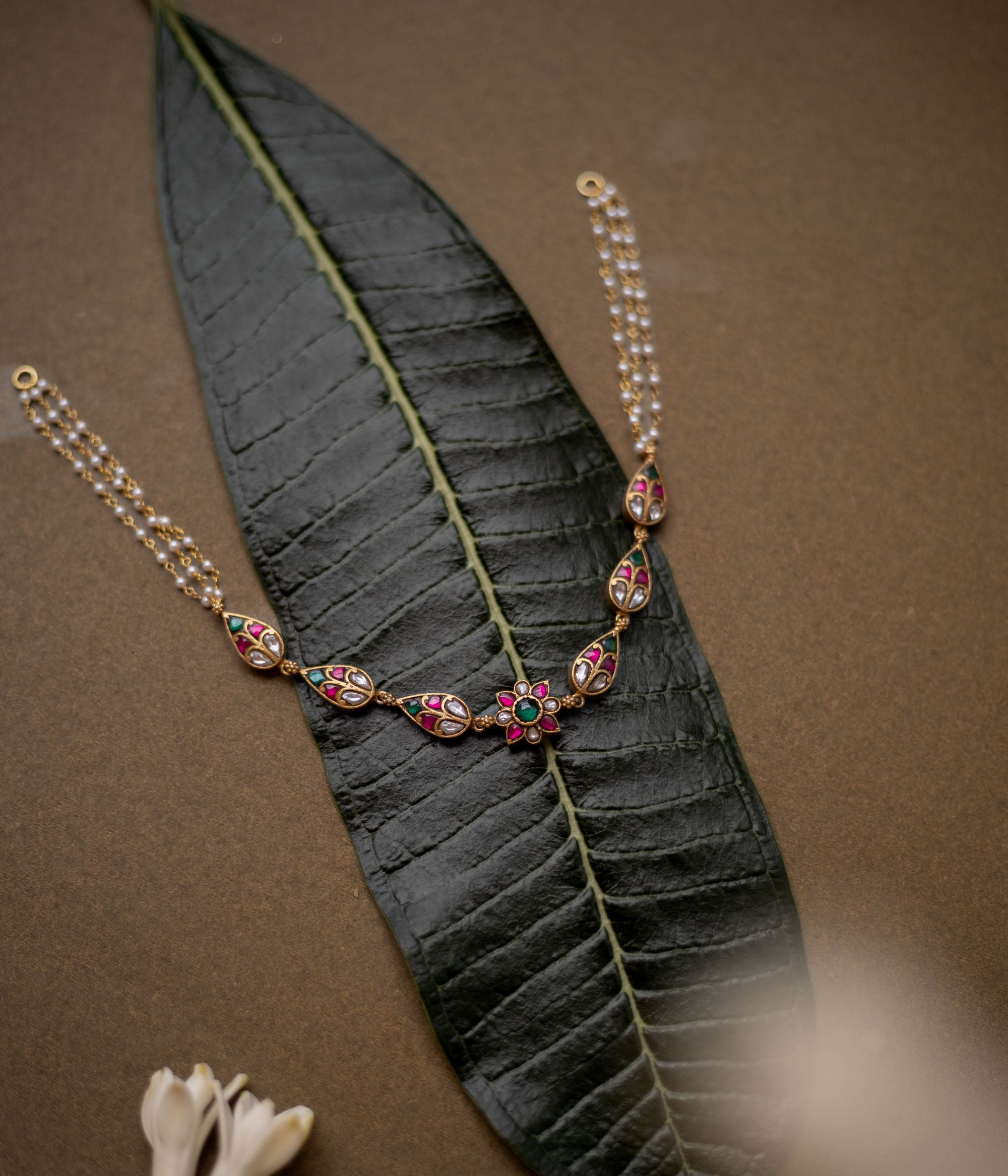 Floral kundan choker with red, green, and white stones and pearl dual chains.