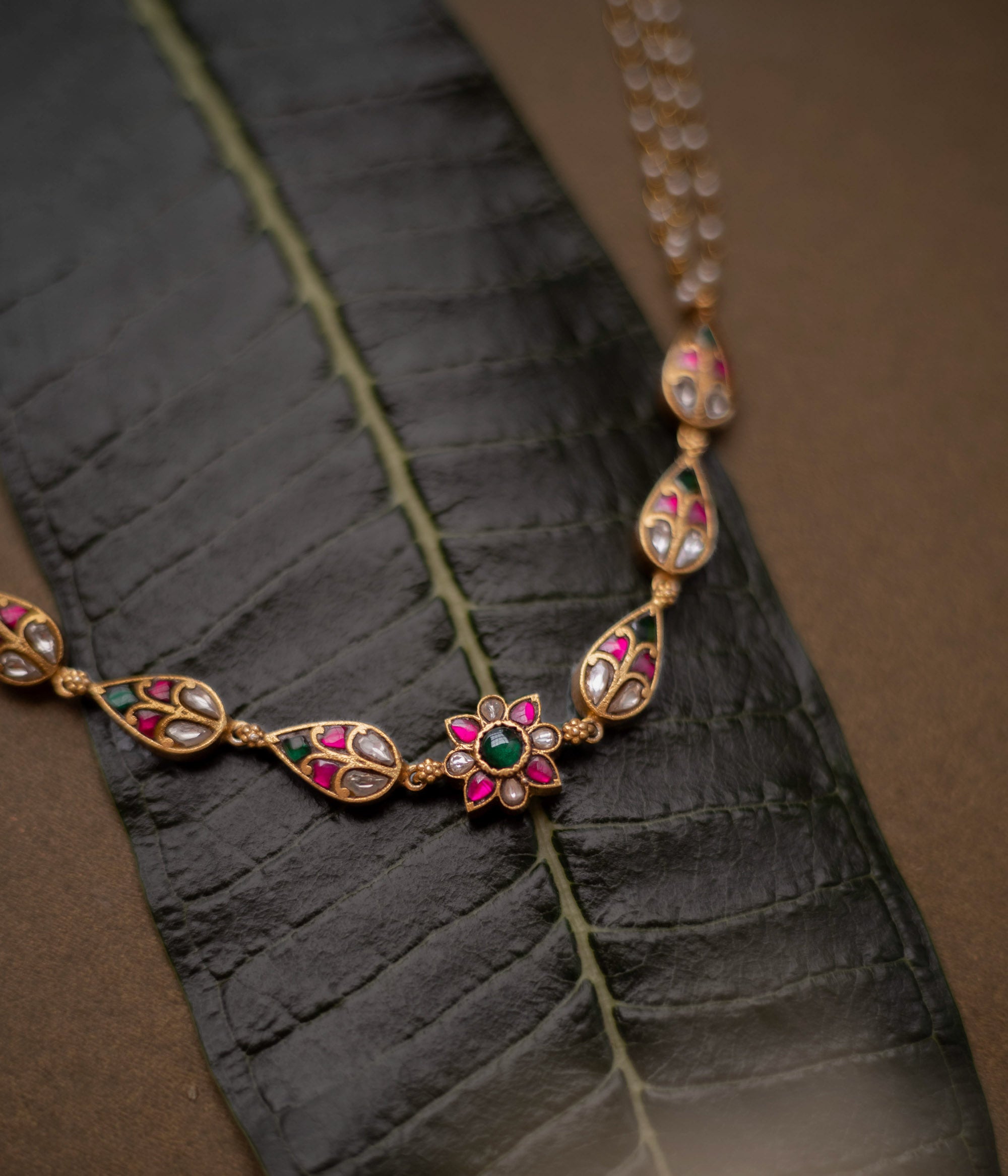 Floral kundan choker with red, green, and white stones and pearl dual chains.