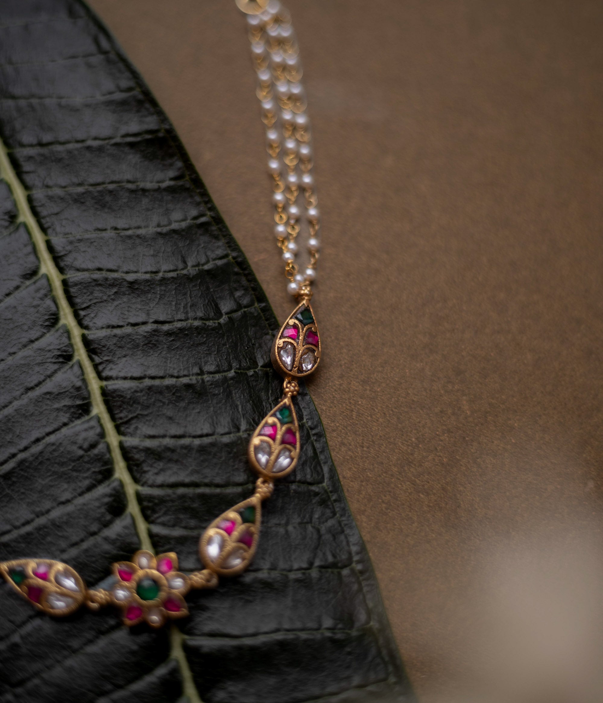 Floral kundan choker with red, green, and white stones and pearl dual chains.