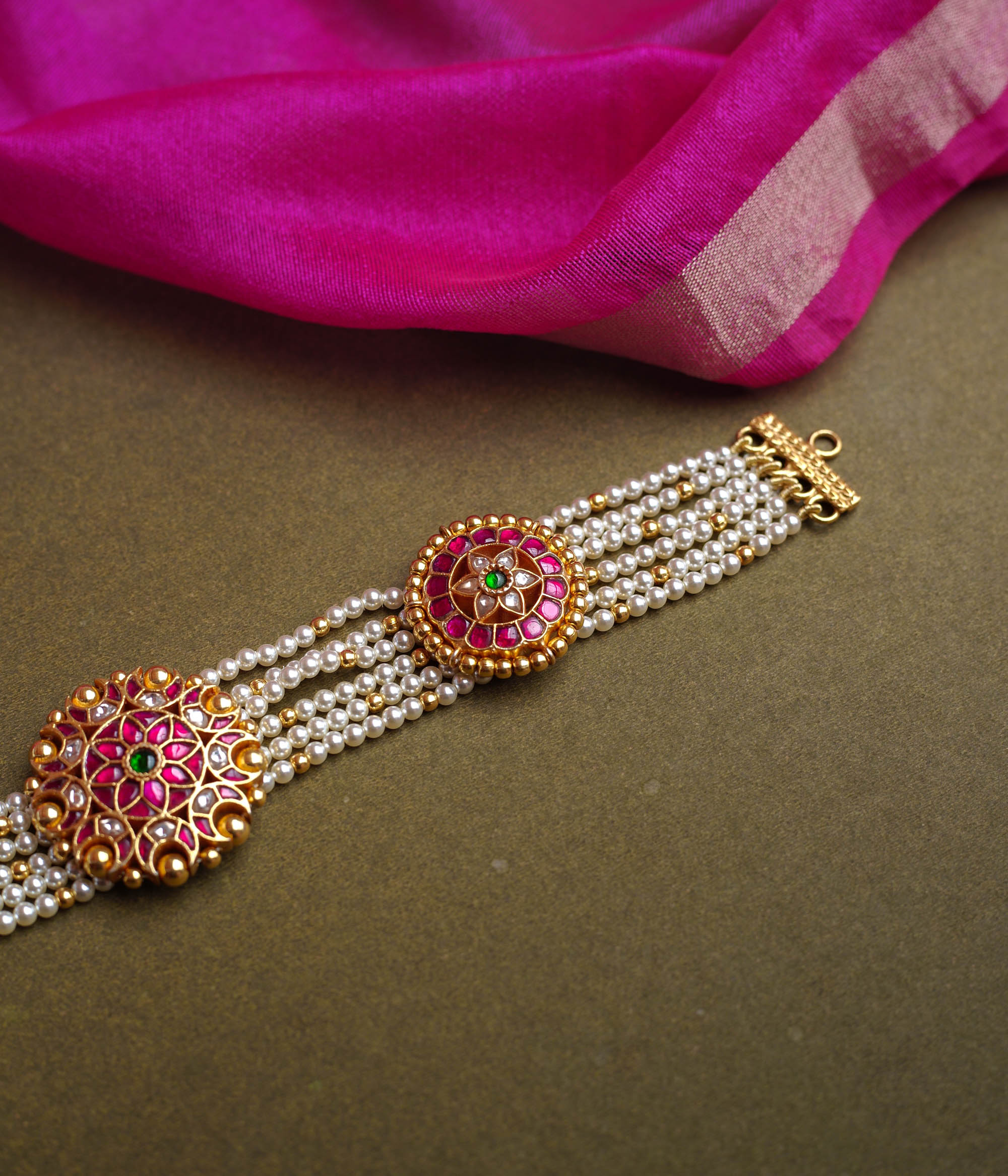 A multi-strand pearl choker featuring three circular, ornate gold Kundan medallions. Each medallion is set with red, green, and white Kundan stones.
