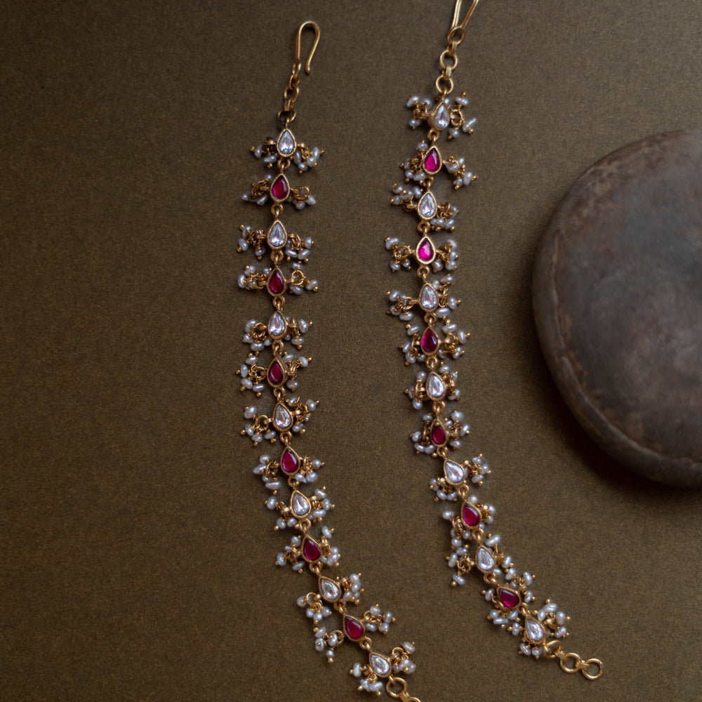 Traditional ear chain with red and white kundan stones and pearl embellishments.