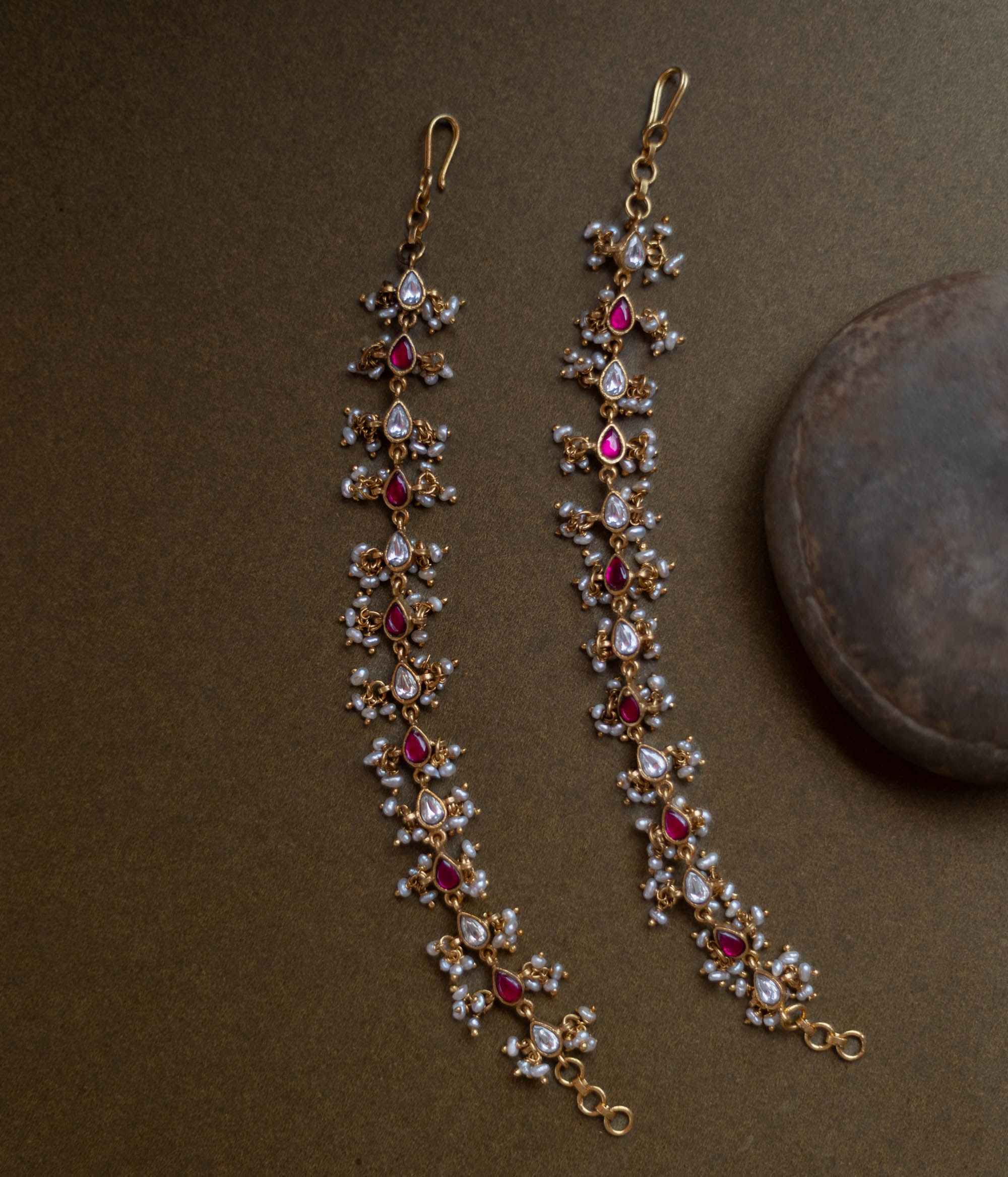 Traditional ear chain with red and white kundan stones and pearl embellishments.
