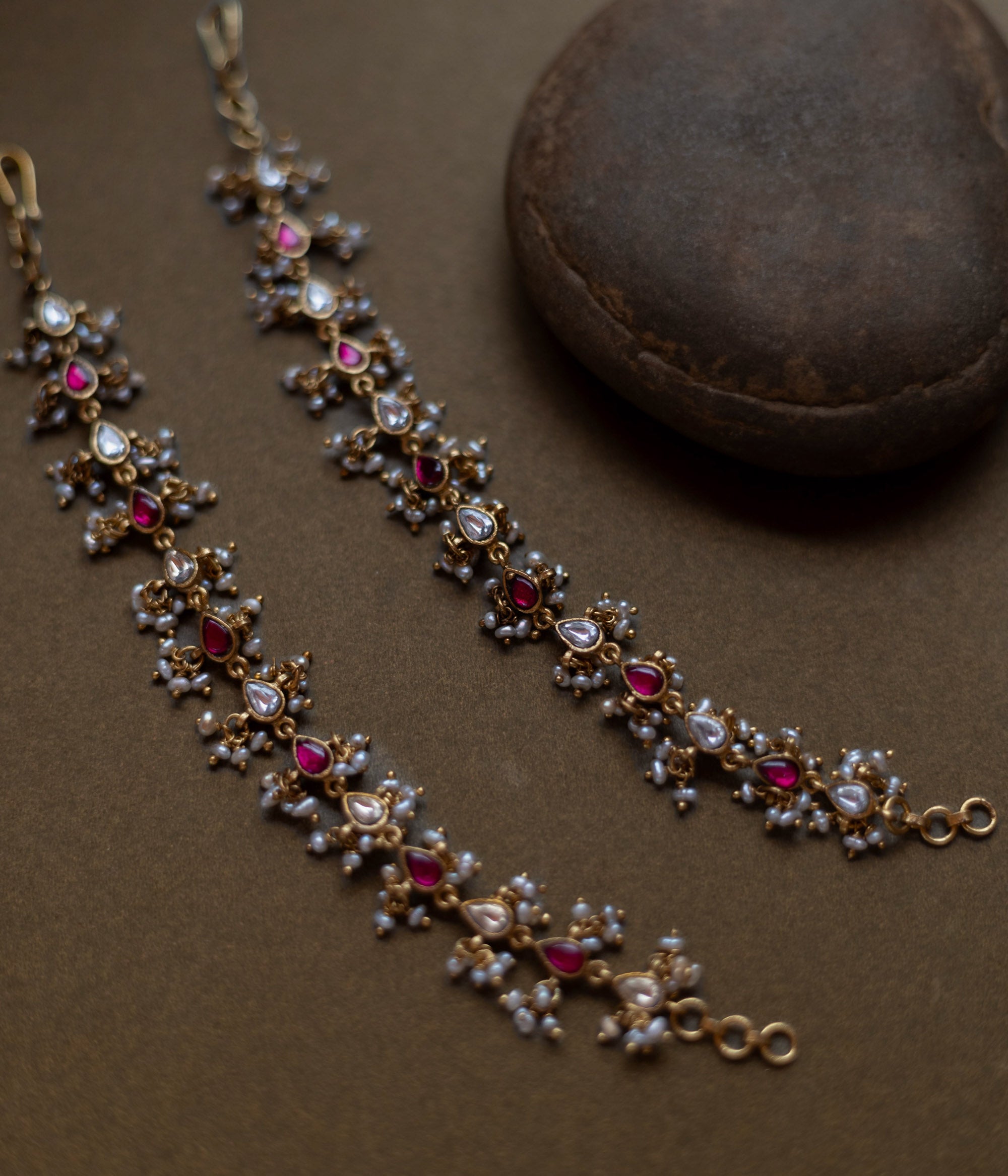 Traditional ear chain with red and white kundan stones and pearl embellishments.