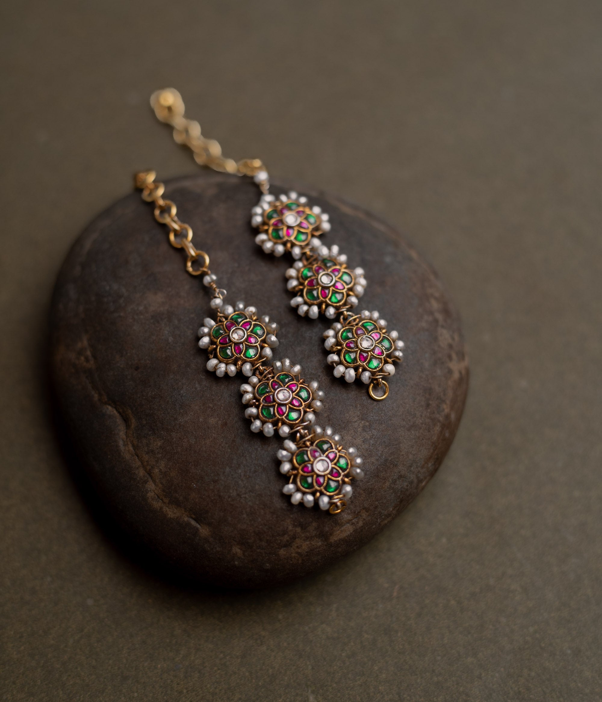 Kundan Collection ear chain with red, green, and white kundan stones enhanced with pearls in regal design.