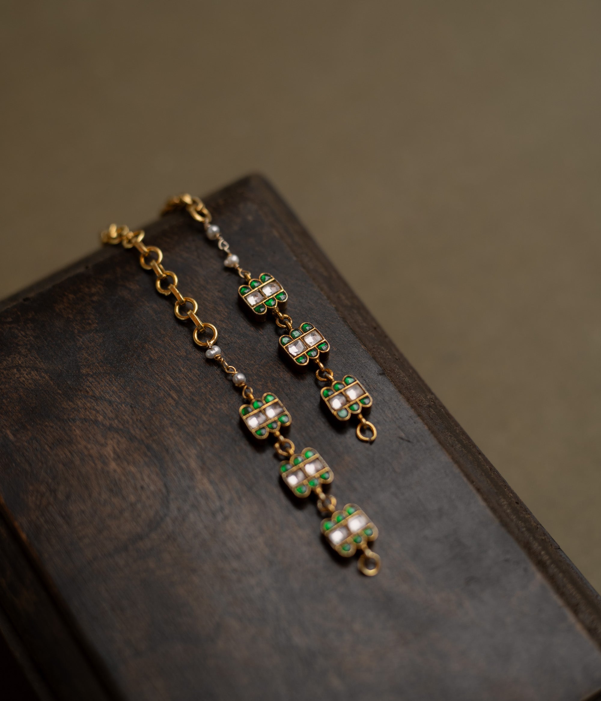 Kundan Collection ear chain with green kundan petals and white kundan stones in blooming vine design.