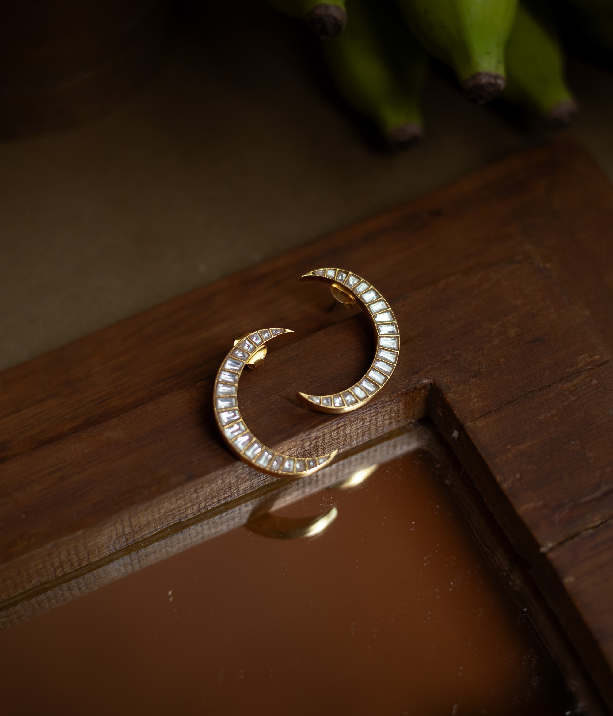 Crescent-shaped Kundan earrings with white stones set in gold, inspired by moonlit elegance.