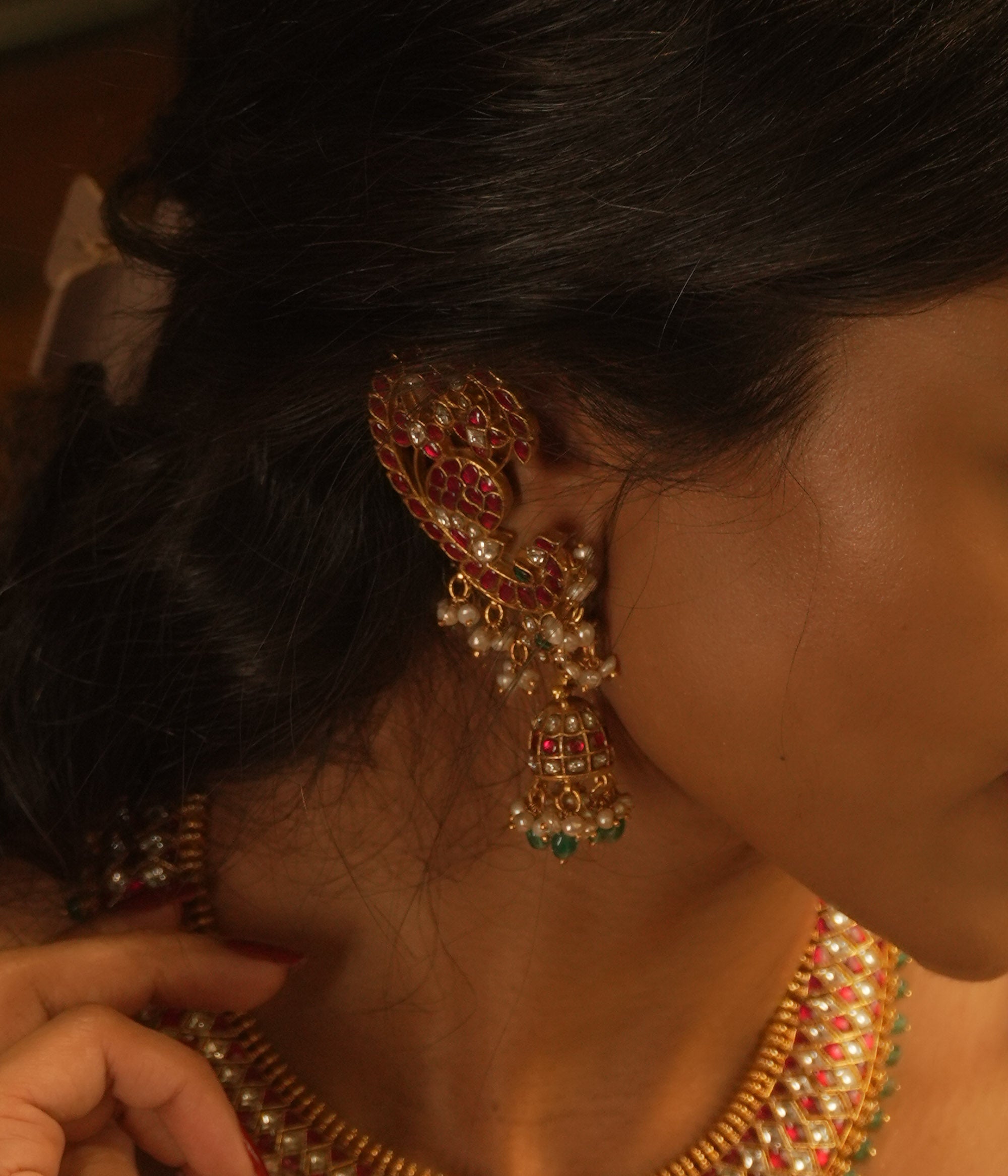 Peacock-inspired kundan earrings with red, green, and white stones, featuring pearl and bead hangings.