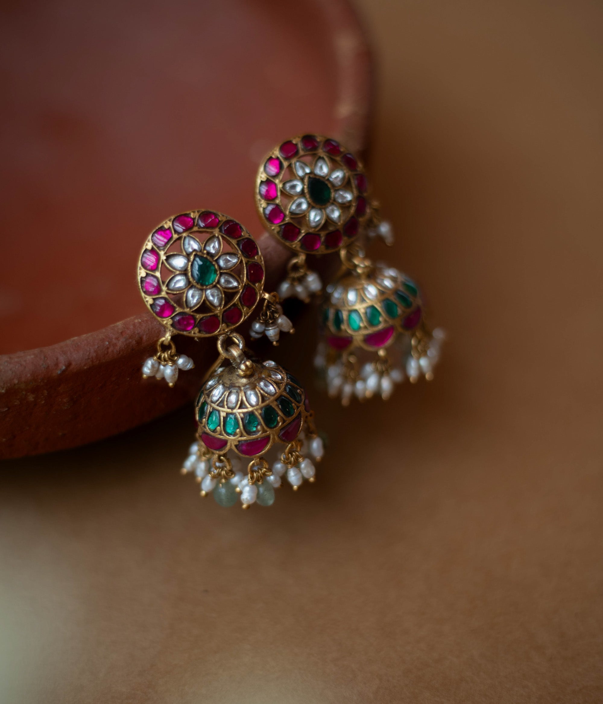 Round floral Kundan earrings with dome-shaped jhumkas, pearls, and green bead hangings.