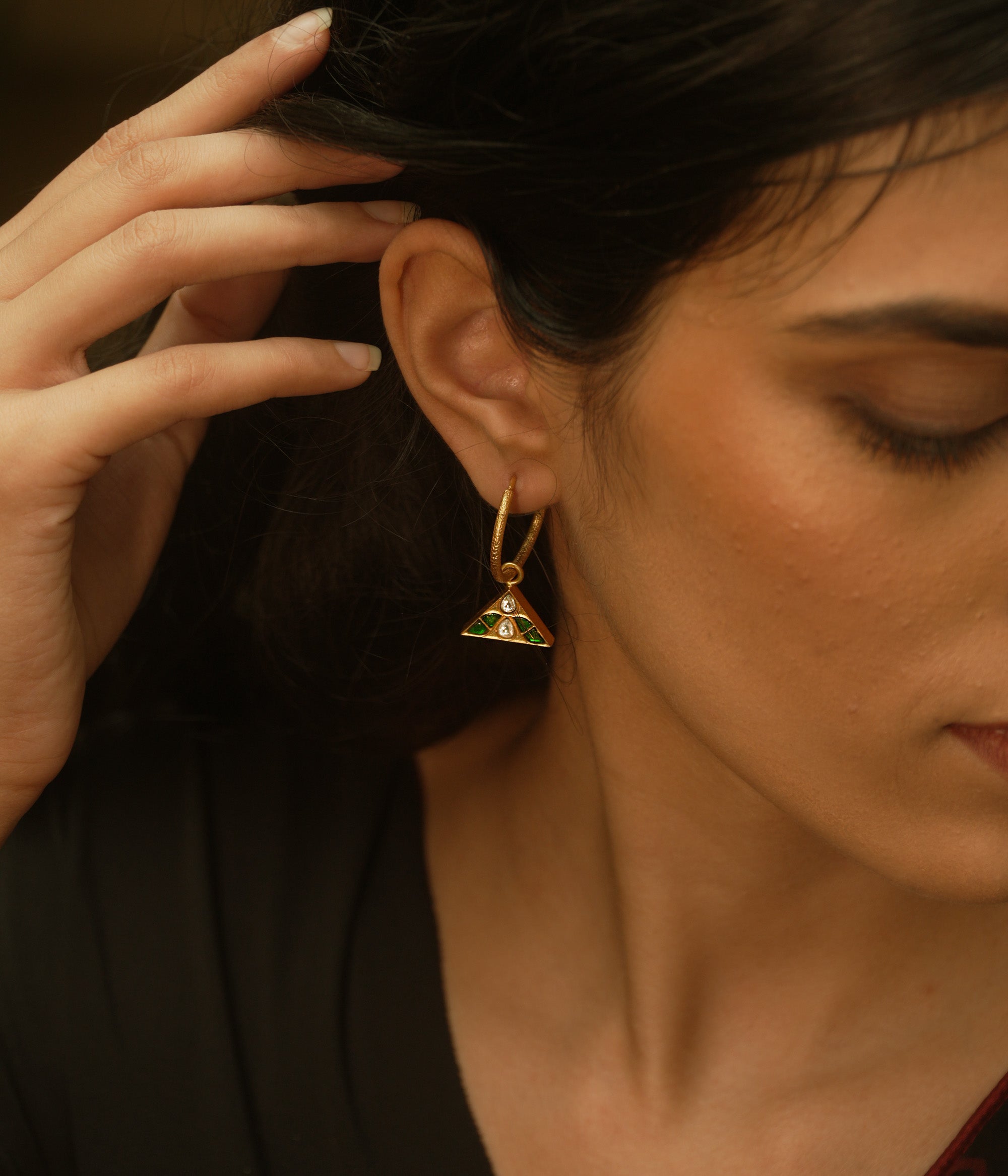 Triangular kundan earrings with reversible green and red kundan stones, accented by a central white kundan.