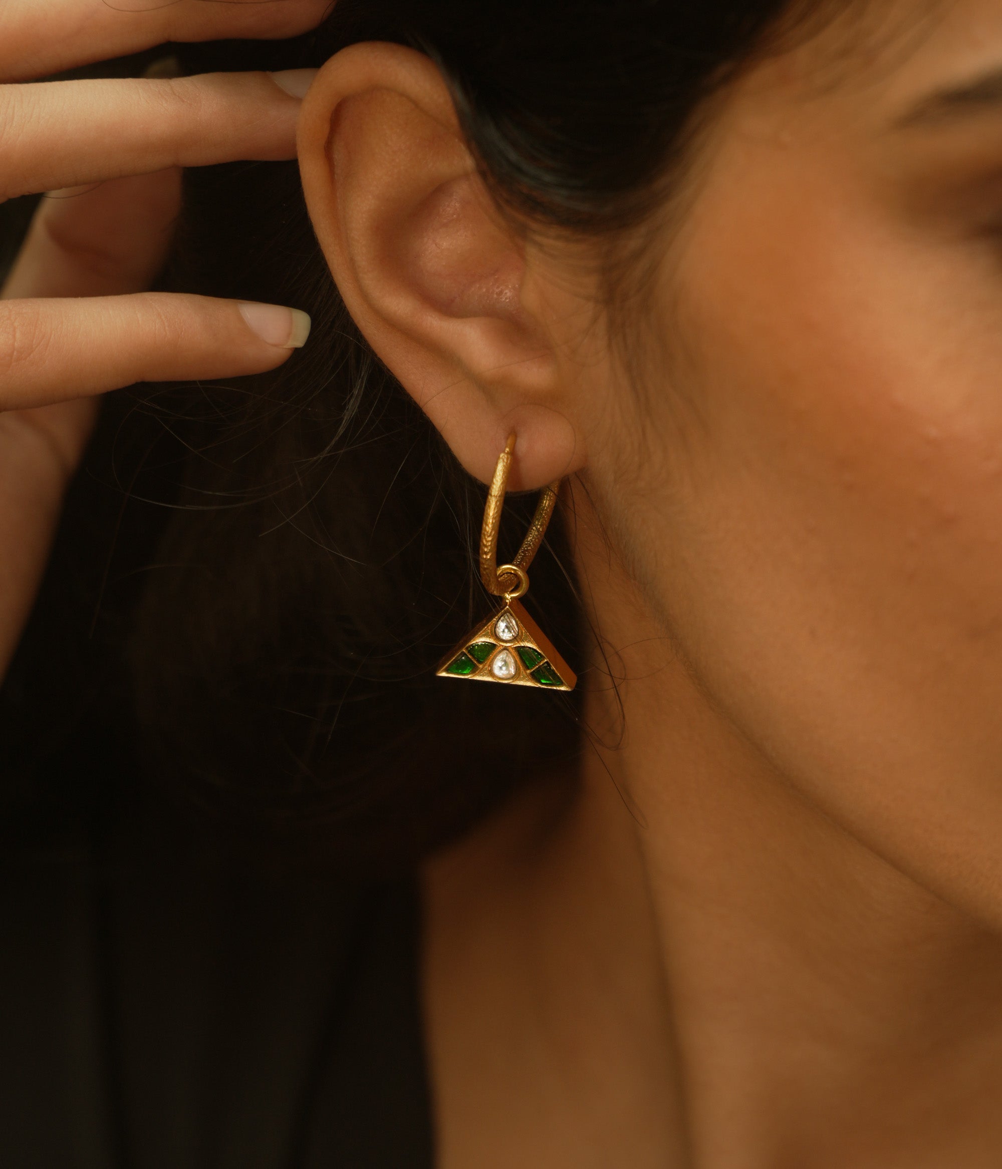 Triangular kundan earrings with reversible green and red kundan stones, accented by a central white kundan.