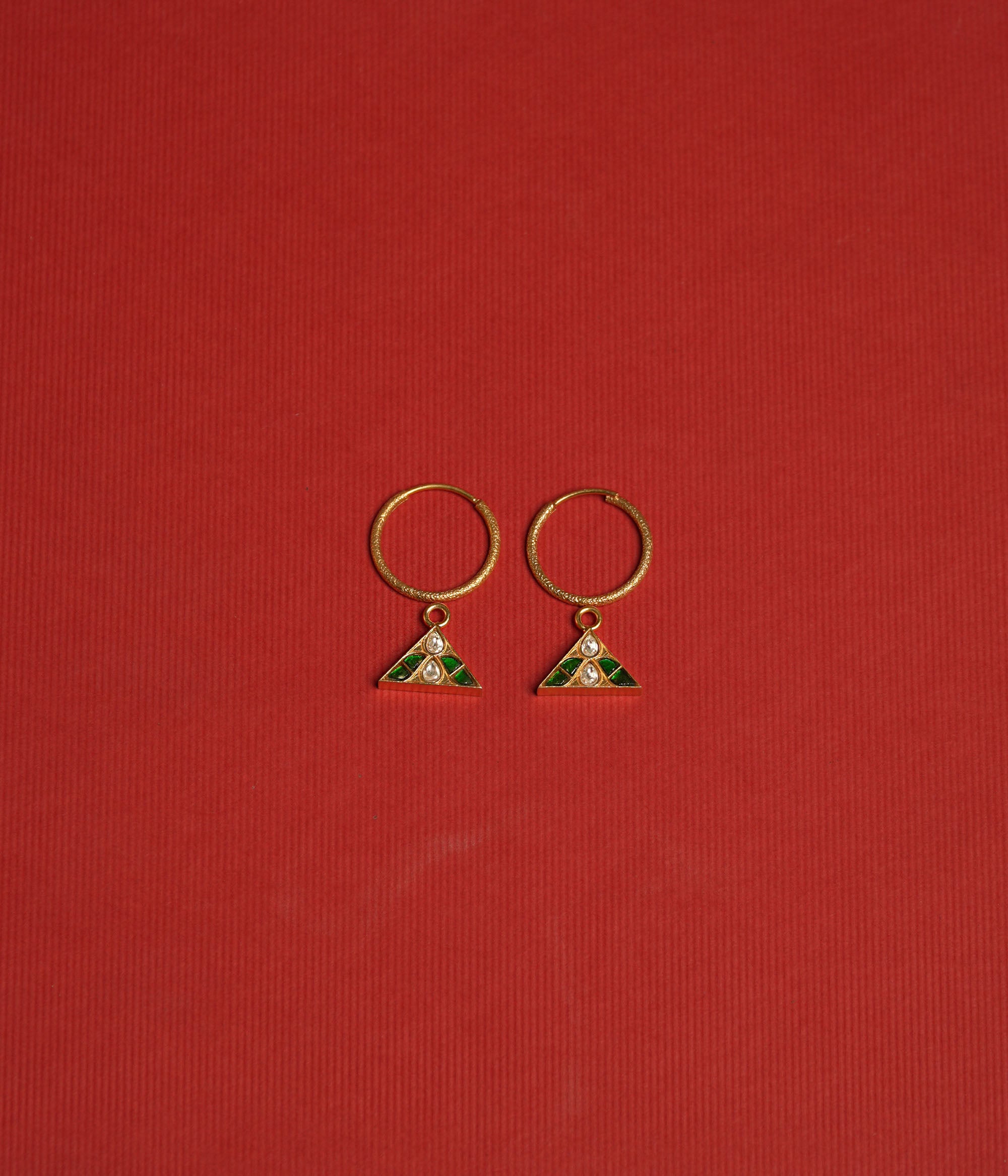 Triangular kundan earrings with reversible green and red kundan stones, accented by a central white kundan.