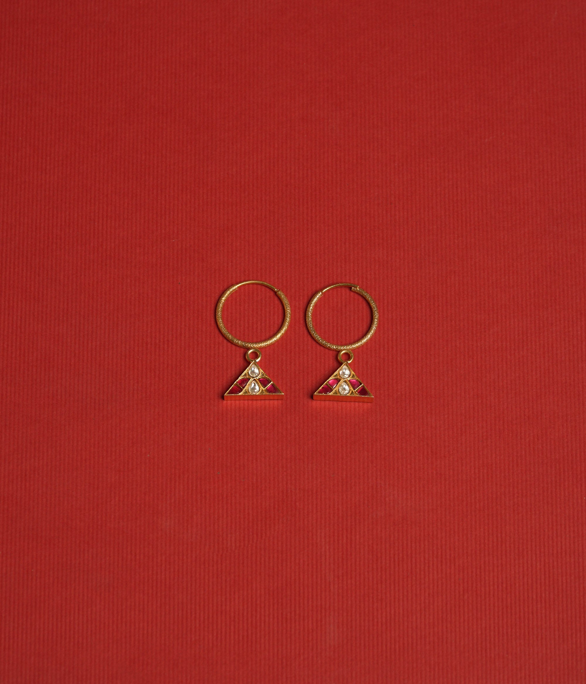 Triangular kundan earrings with reversible green and red kundan stones, accented by a central white kundan.