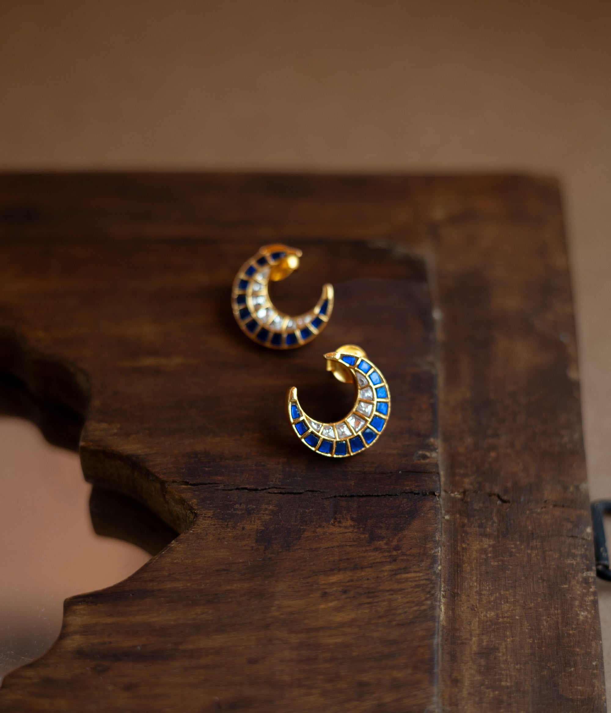 Teardrop earrings with a floral pattern of blue and white Kundan stones and a hanging pearl.