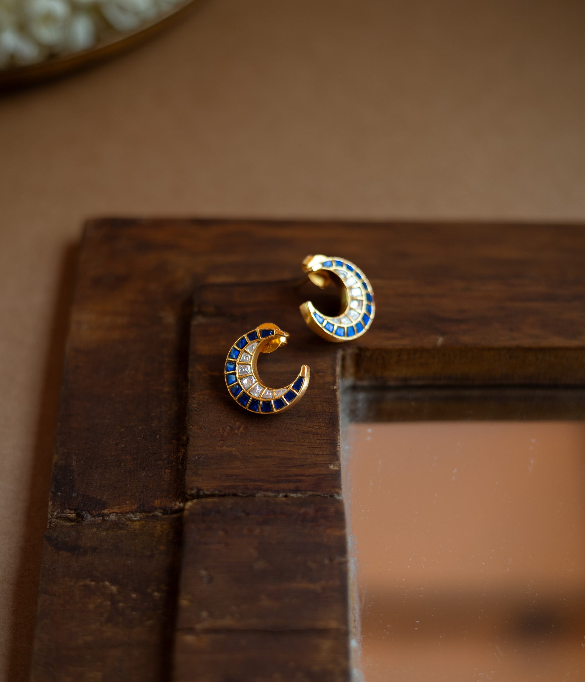 Teardrop earrings with a floral pattern of blue and white Kundan stones and a hanging pearl.