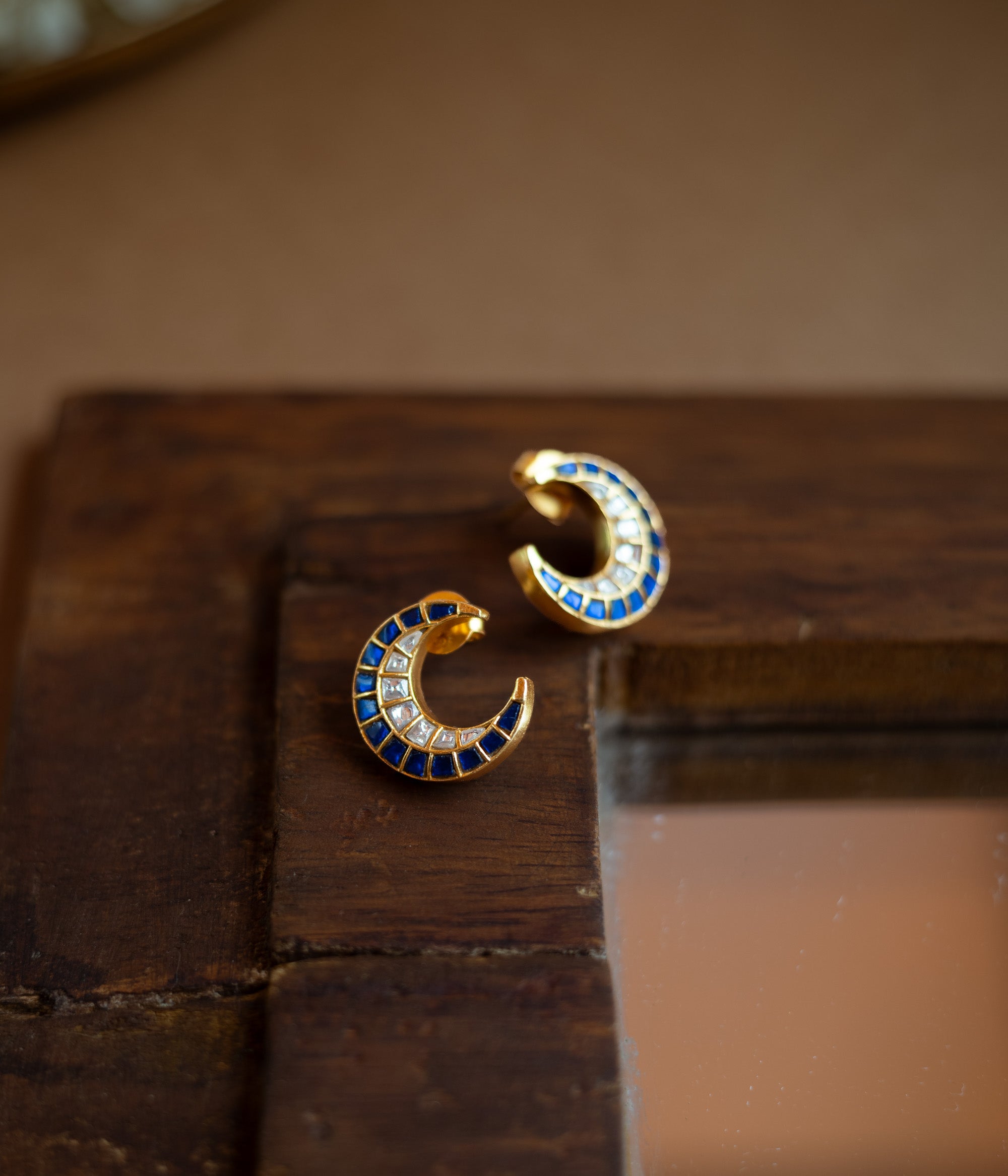 Teardrop earrings with a floral pattern of blue and white Kundan stones and a hanging pearl.