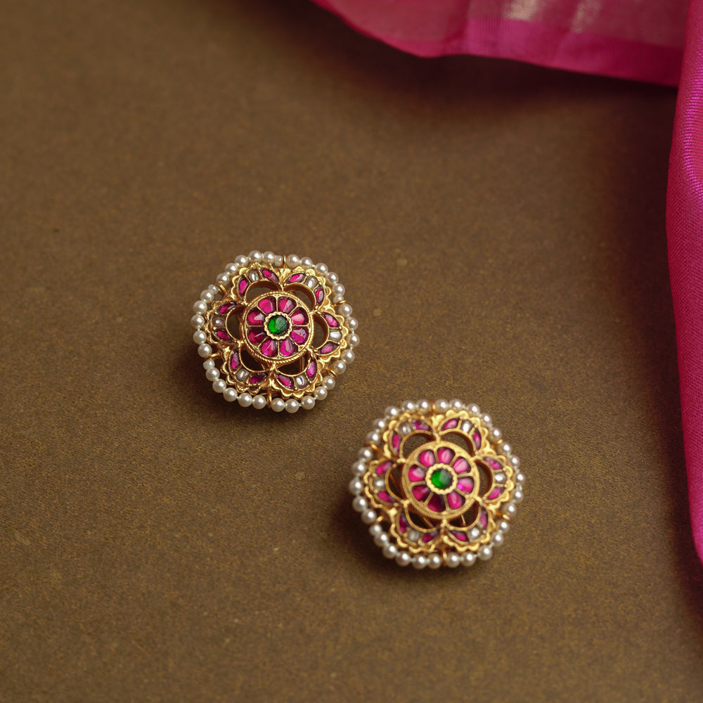 Lotus-inspired gold earrings with red, green, and white Kundan stones bordered by tiny pearls.