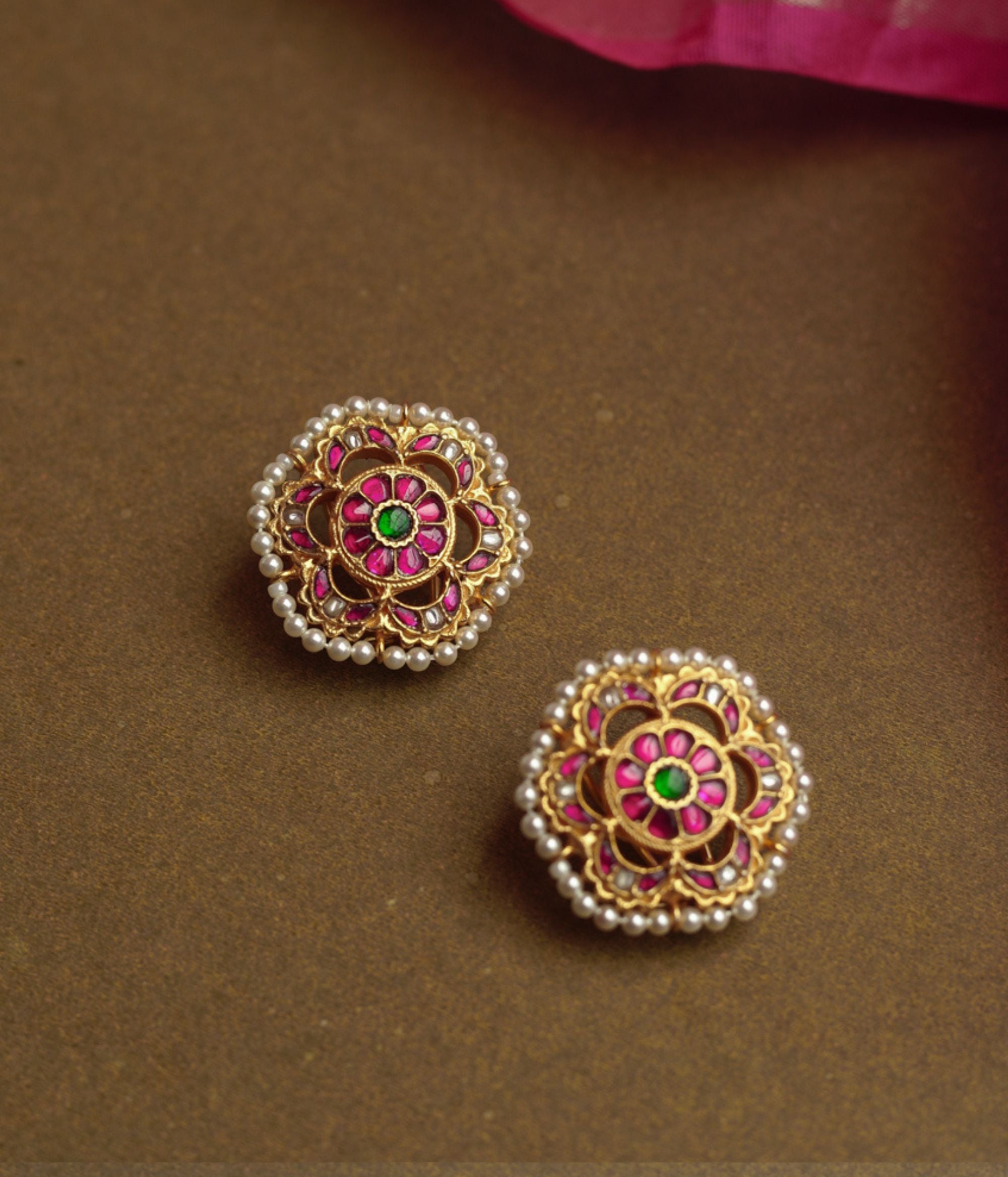 Lotus-inspired gold earrings with red, green, and white Kundan stones bordered by tiny pearls.