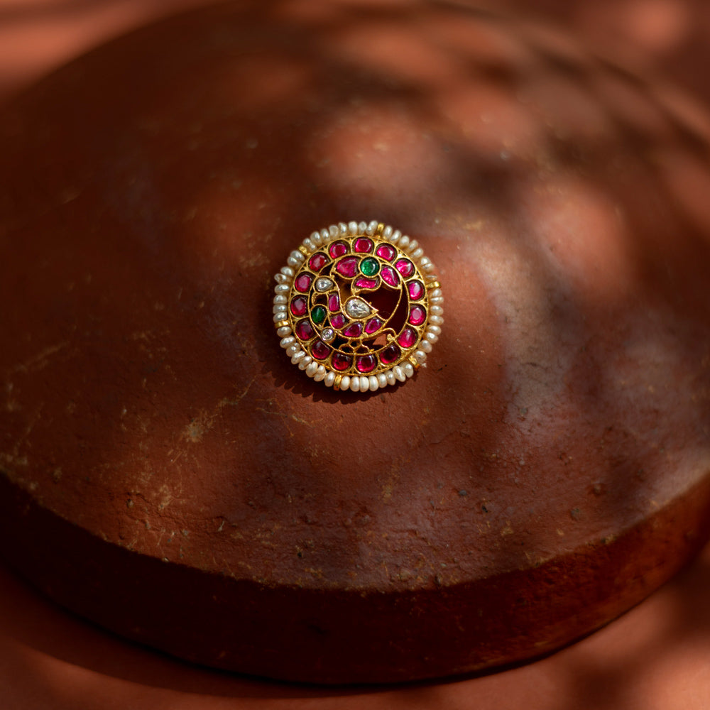 Gold-framed hairpin with vibrant red and green kundan stones and lustrous pearls, inspired by classical Indian motifs for a regal traditional hairstyle.
