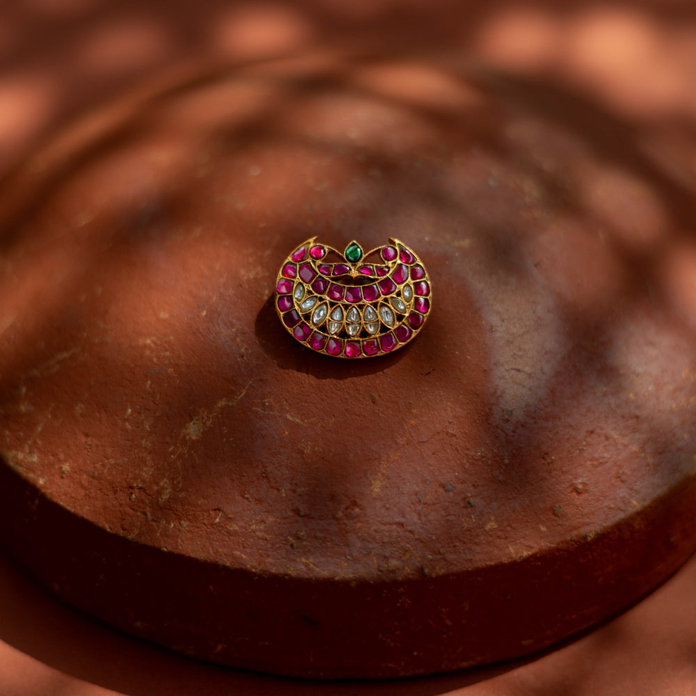 Crescent-shaped hairpin with rich pink and white kundan stones and a single emerald green accent, symbolizing youth and radiance for ethnic ensembles.