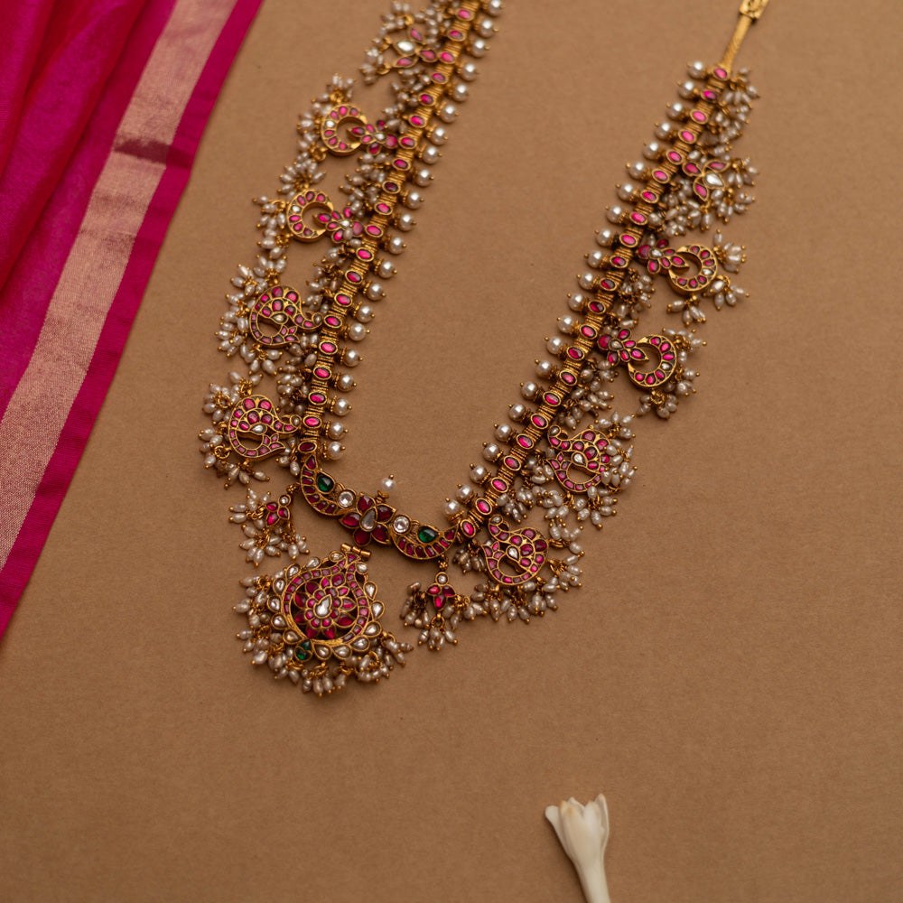 Grand temple-inspired Kundan necklace with shimmering stones, vibrant ruby and emerald accents, and delicate pearl clusters, perfect for weddings and divine celebrations.