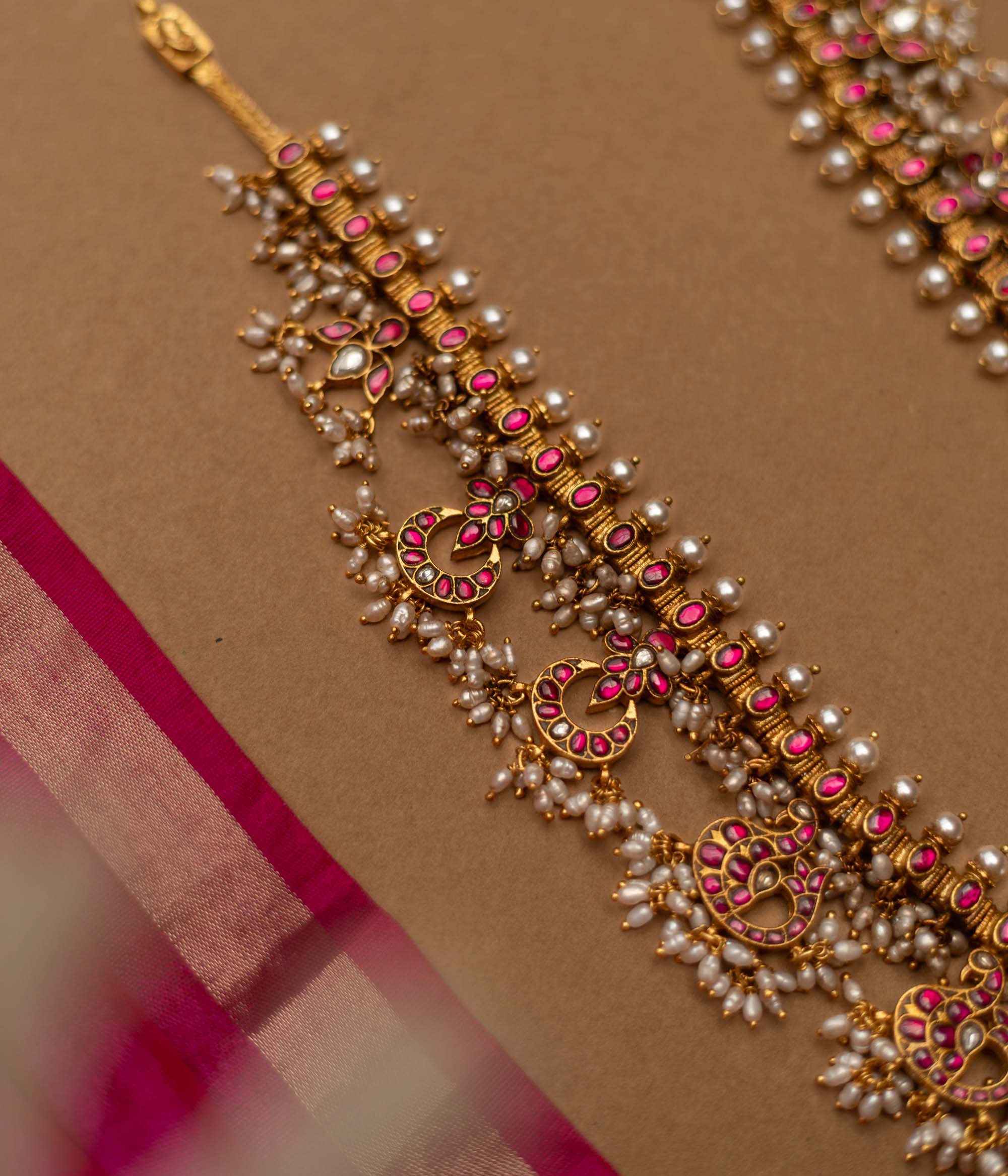 Grand temple-inspired Kundan necklace with shimmering stones, vibrant ruby and emerald accents, and delicate pearl clusters, perfect for weddings and divine celebrations.