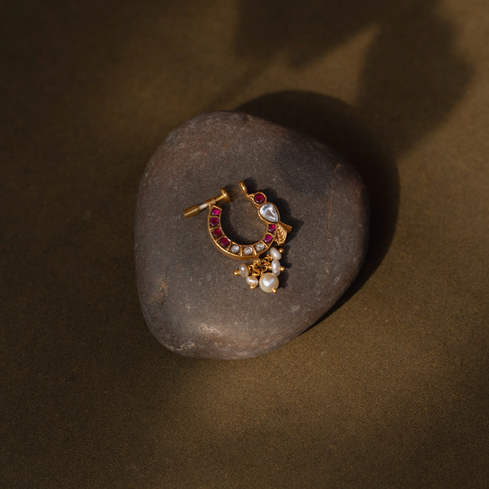 A delicate yet regal 92.5 sterling silver Rani Kemp Nath nosepin featuring vibrant red and white Kundan stones, a single teardrop-shaped white stone, and delicate dangling pearls set in a gold-plated framework, perfect for adding traditional Indian elegance.