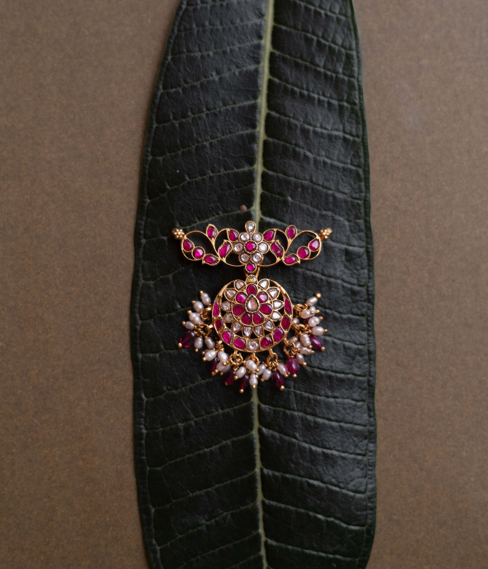 Lotus-inspired kundan pendant with red and white stones, pearl fringe, and circular floral design.
