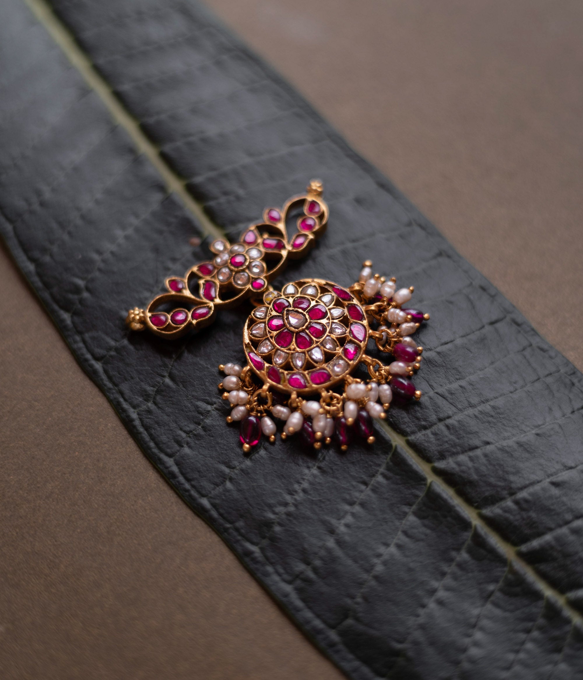 Lotus-inspired kundan pendant with red and white stones, pearl fringe, and circular floral design.