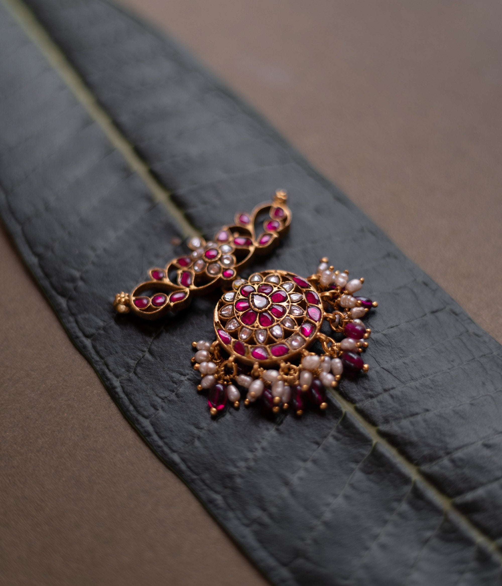 Lotus-inspired kundan pendant with red and white stones, pearl fringe, and circular floral design.