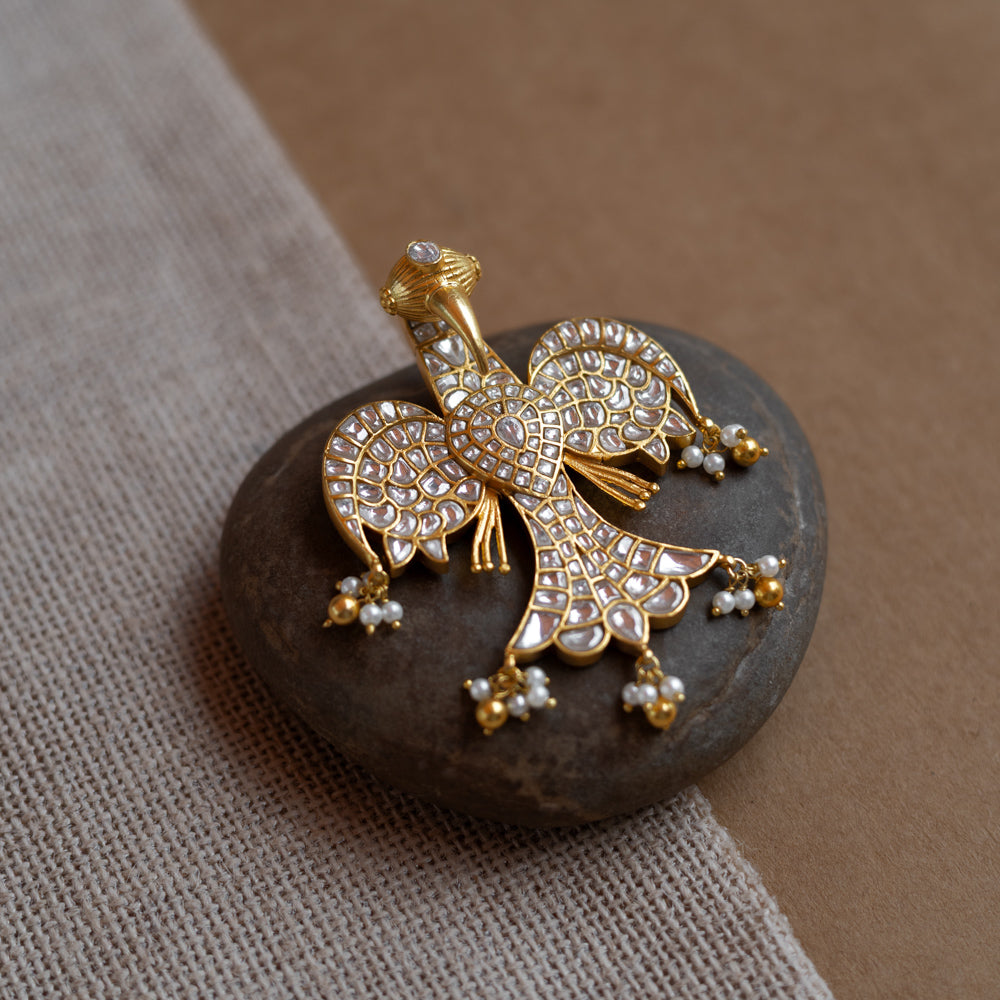 Peacock-shaped kundan pendant with white stones and pearl hangings in a traditional gold design.