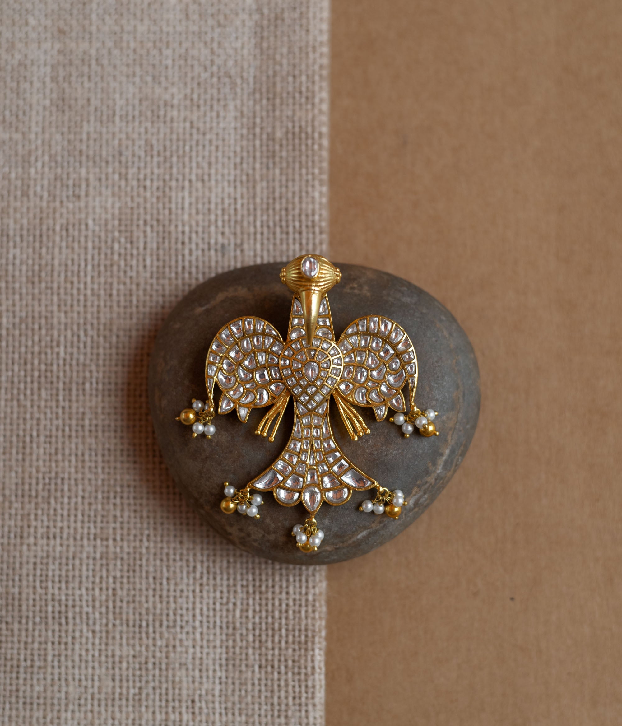 Peacock-shaped kundan pendant with white stones and pearl hangings in a traditional gold design.