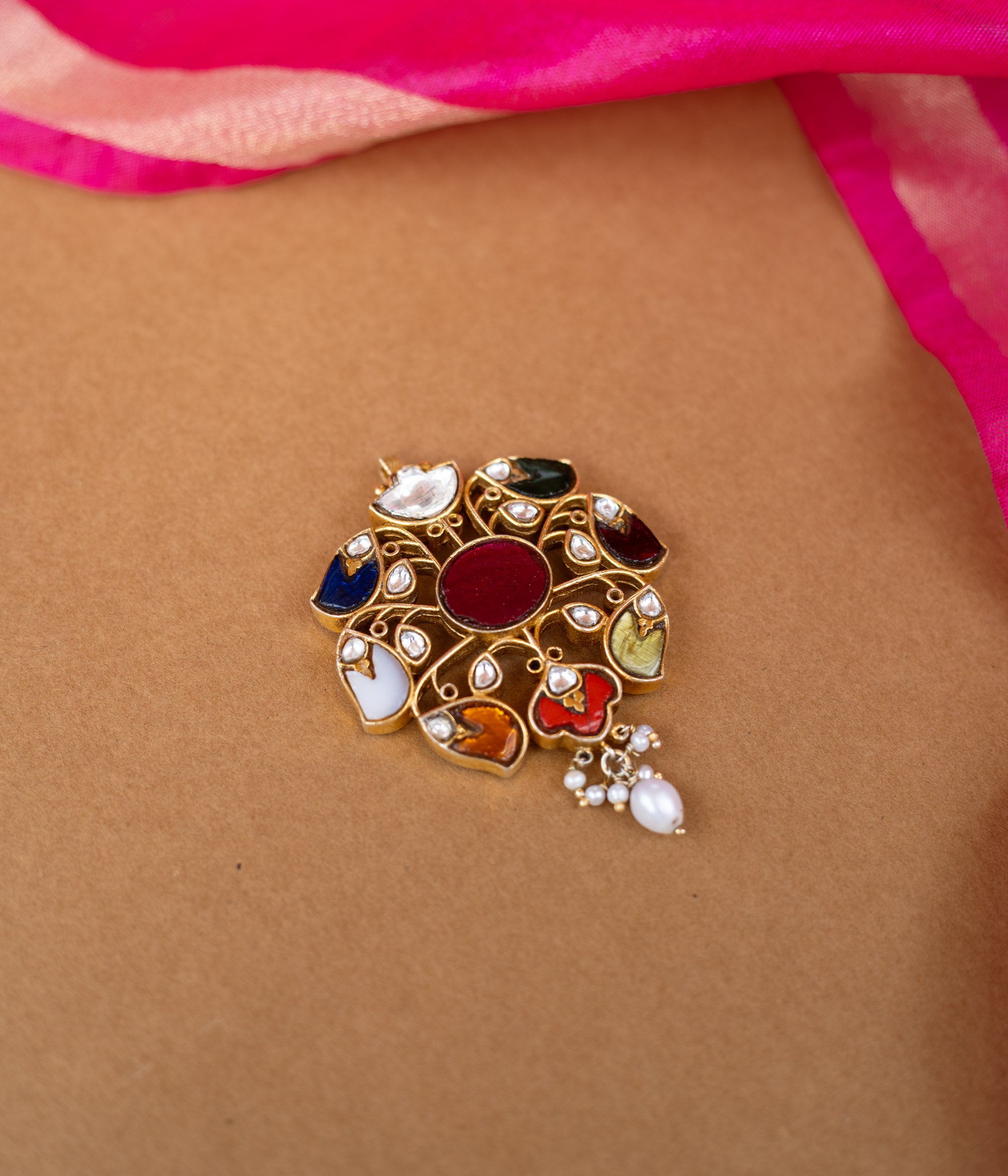 A round Kundan pendant with a central stone and dangling pearl drops.