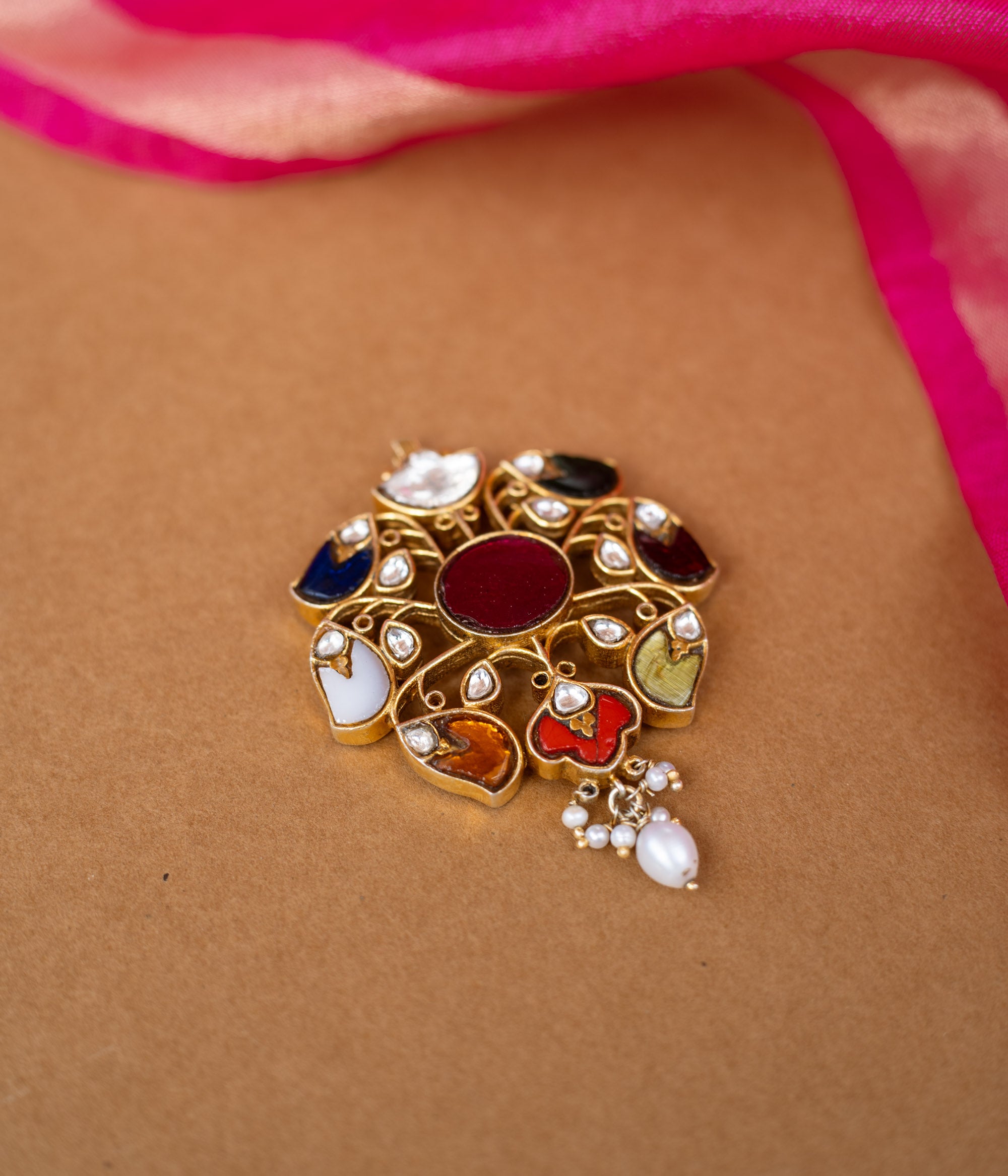 A round Kundan pendant with a central stone and dangling pearl drops.