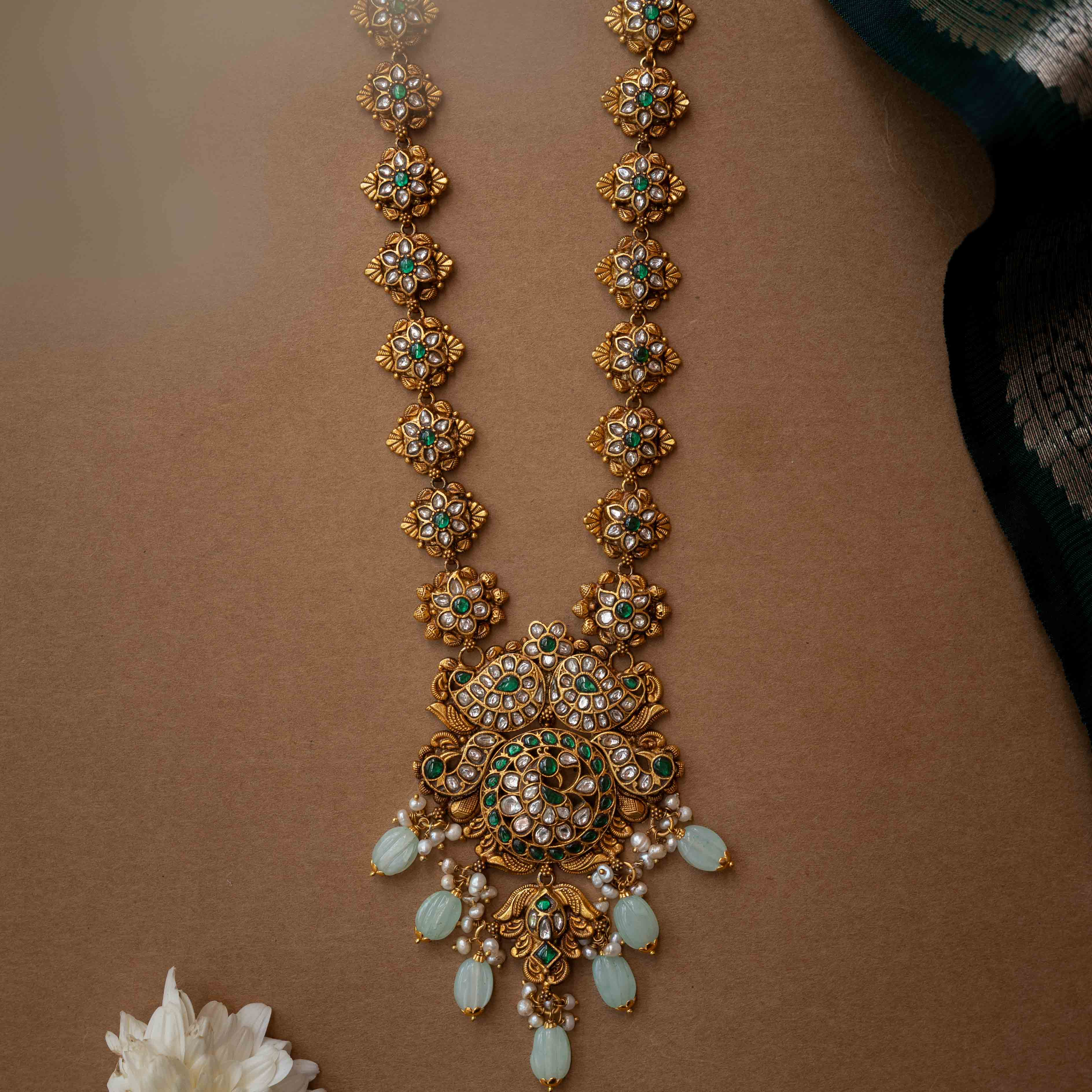 A multi-layered necklace with a central Kundan pendant and cascading strands of pearls and beads.