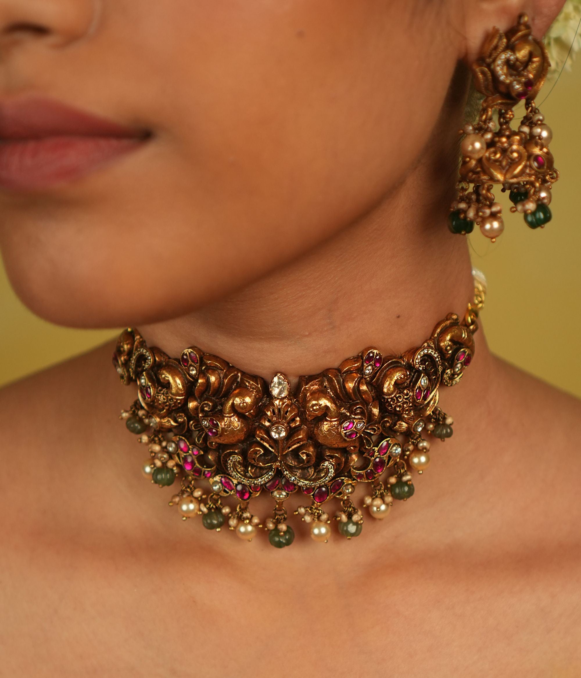 A peacock-inspired choker adorned with red, white, and green kundan, polki, and CZ stones, with delicate green and white bead droplets. More than an adornment, it is a timeless tribute to culture and divine beauty.